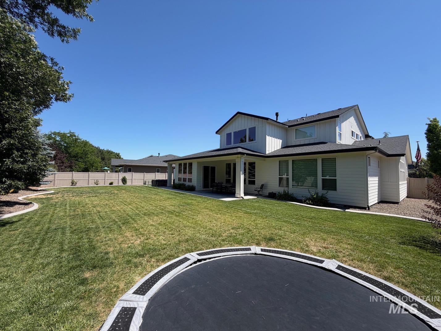Spacious backyard featuring a manicured lawn, perimeter fencing, and mature trees