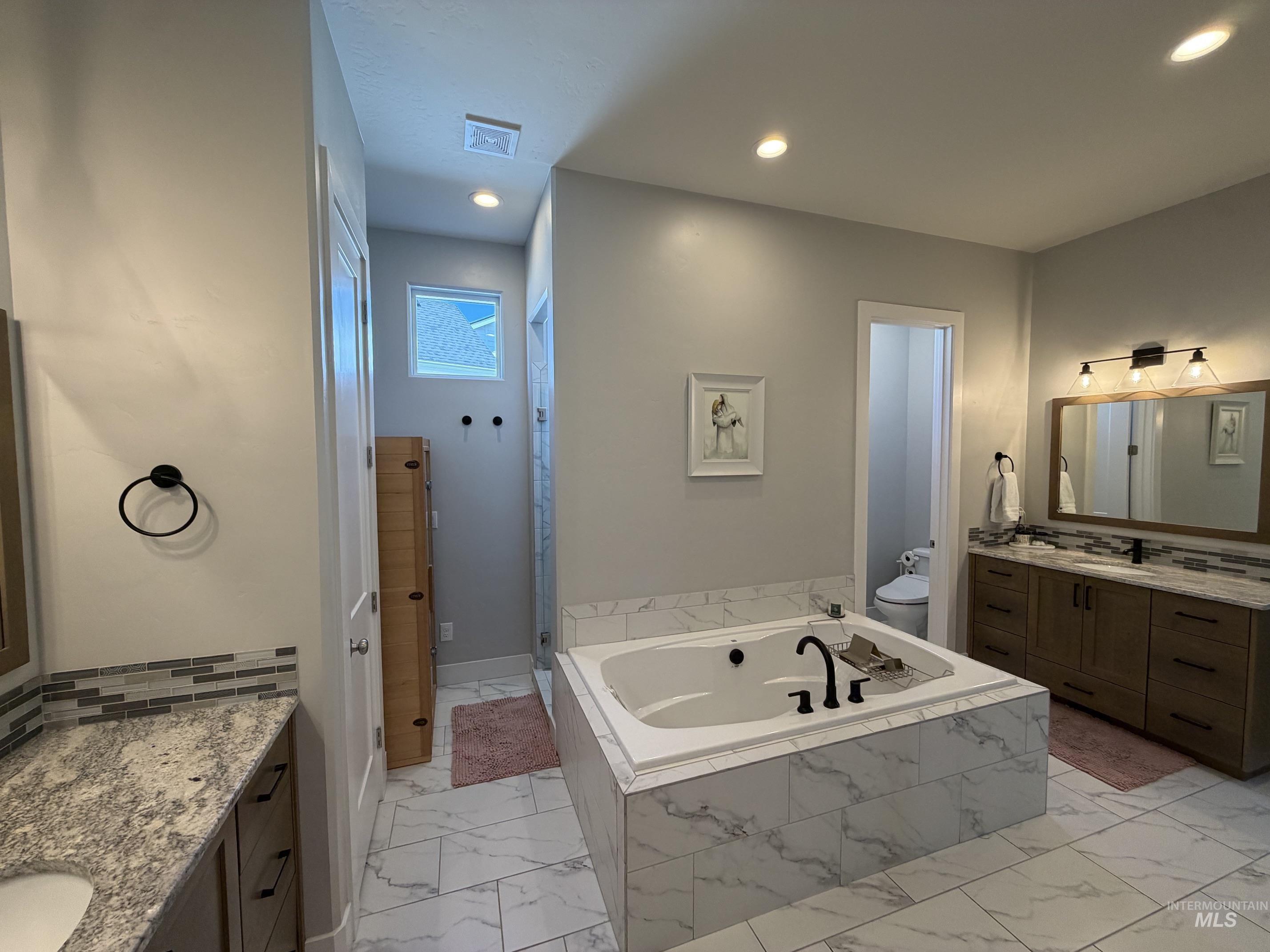 Soaking tub with black fixtures, surrounded by large format tile