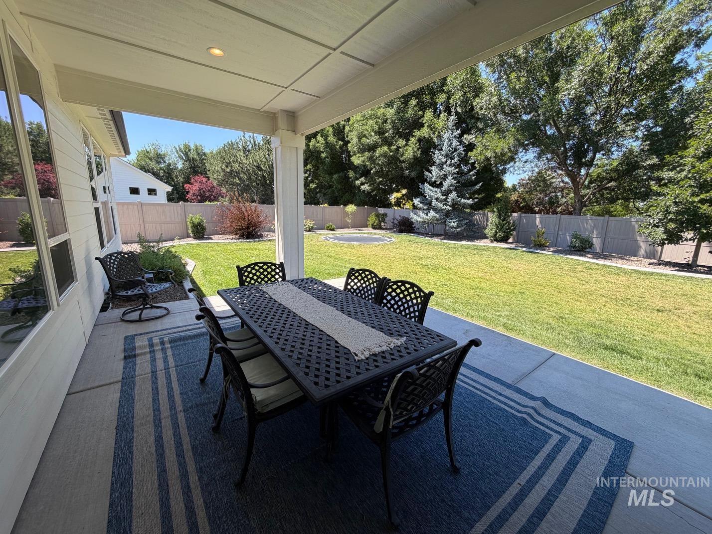 Covered patio featuring a concrete slab, recessed lighting, and a view of the expansive lawn with mature trees and shrubbery