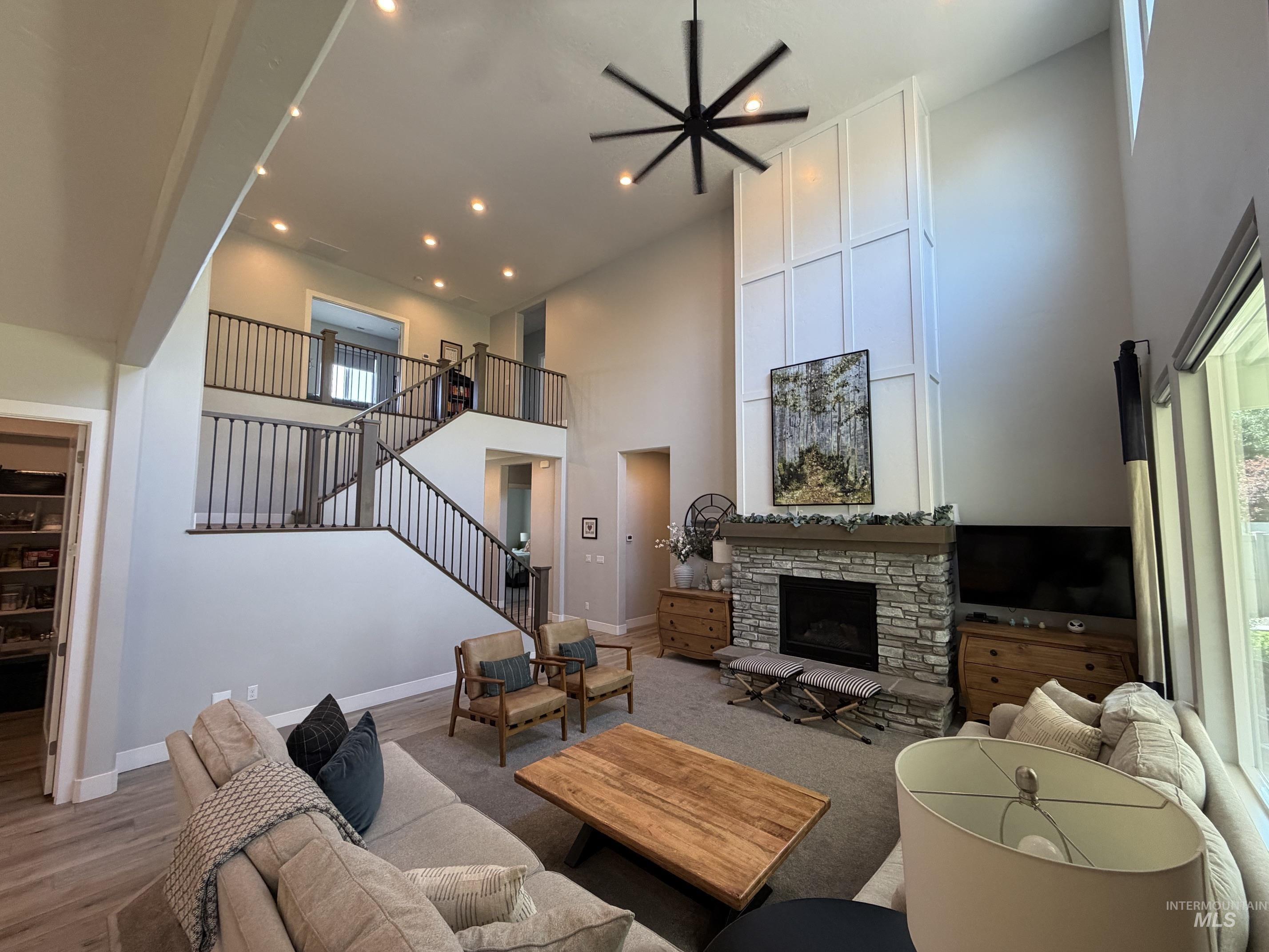 Two-story living area featuring a stone fireplace with a wood mantle, a paneled accent wall, and a multi-level staircase with iron balusters