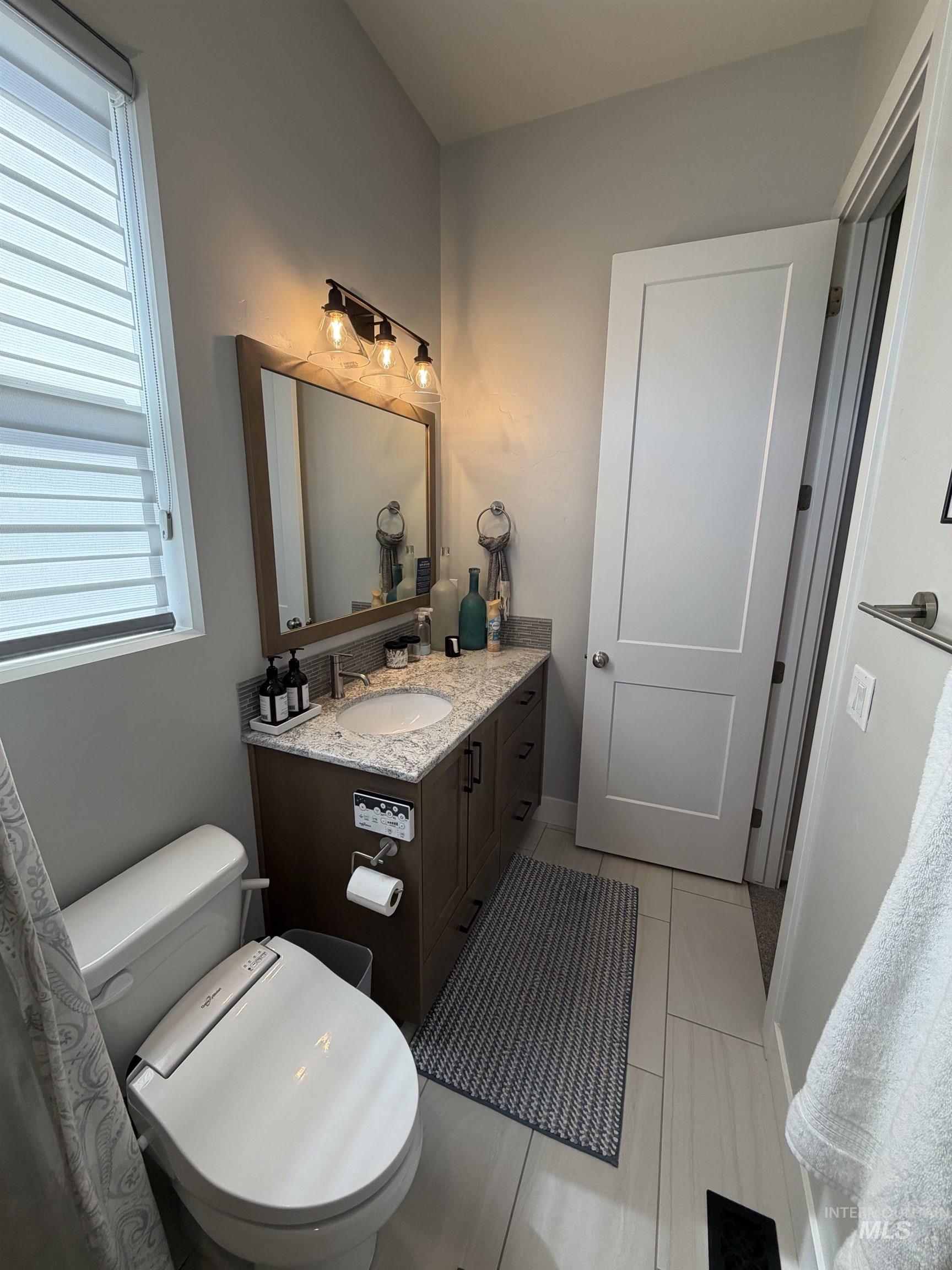 Bathroom featuring a wood-finish vanity with a light-toned countertop and integrated sink