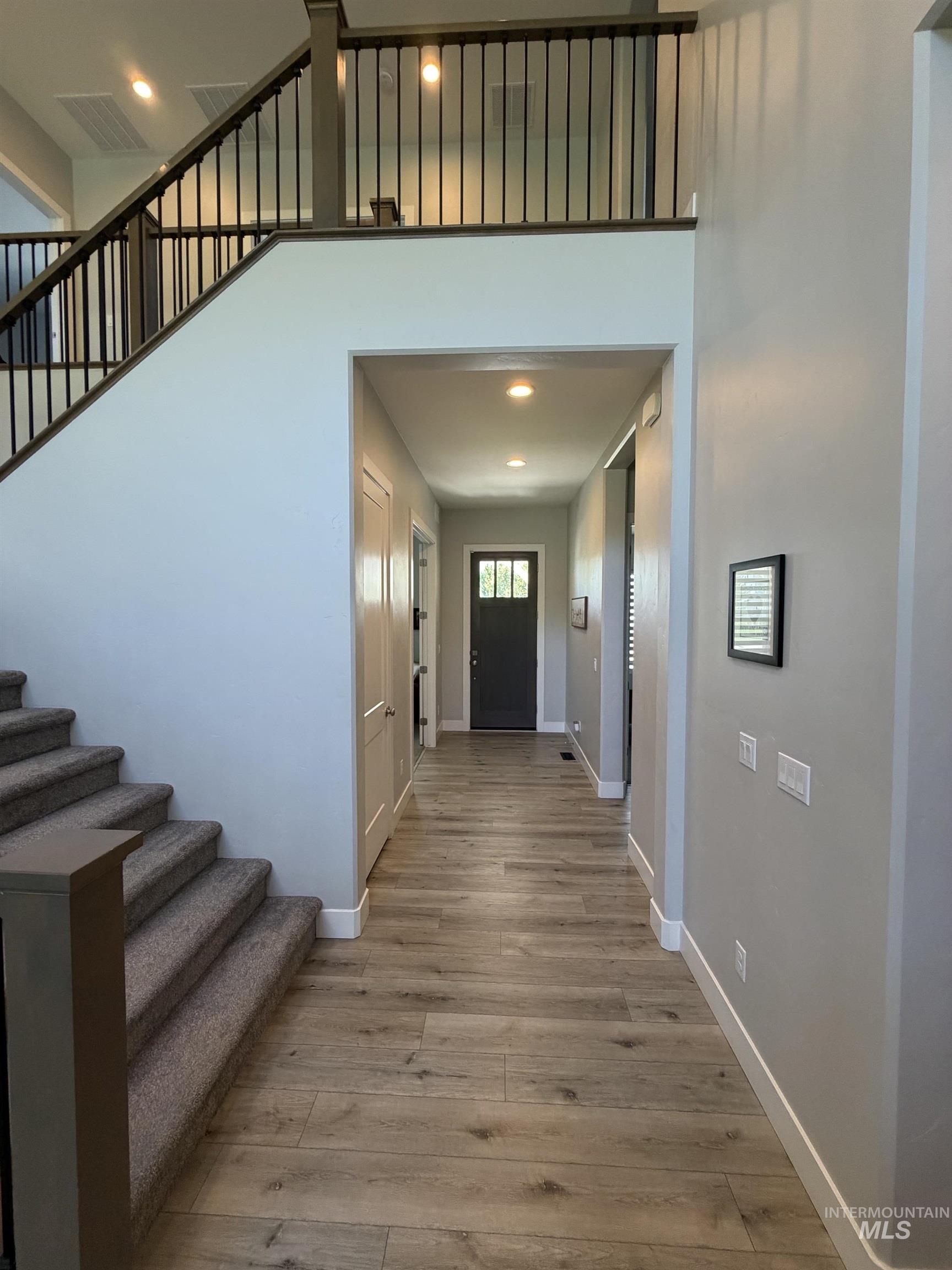 Foyer featuring wood-finish flooring, recessed lighting, and a dark front door with glass panels