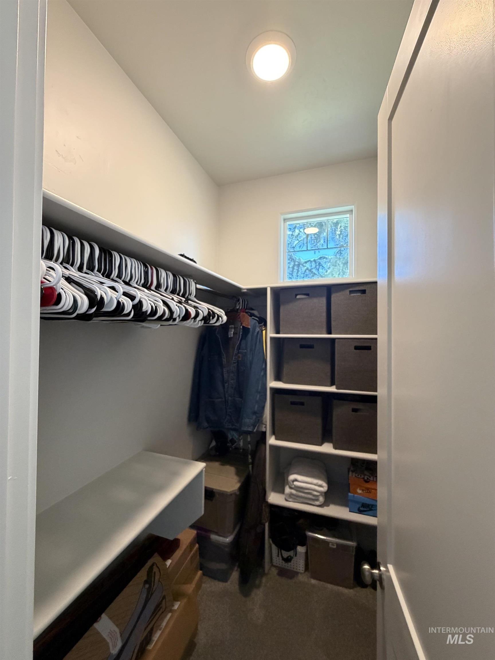 Walk-in closet featuring built-in shelving, hanging rods, recessed ceiling lighting, and a window