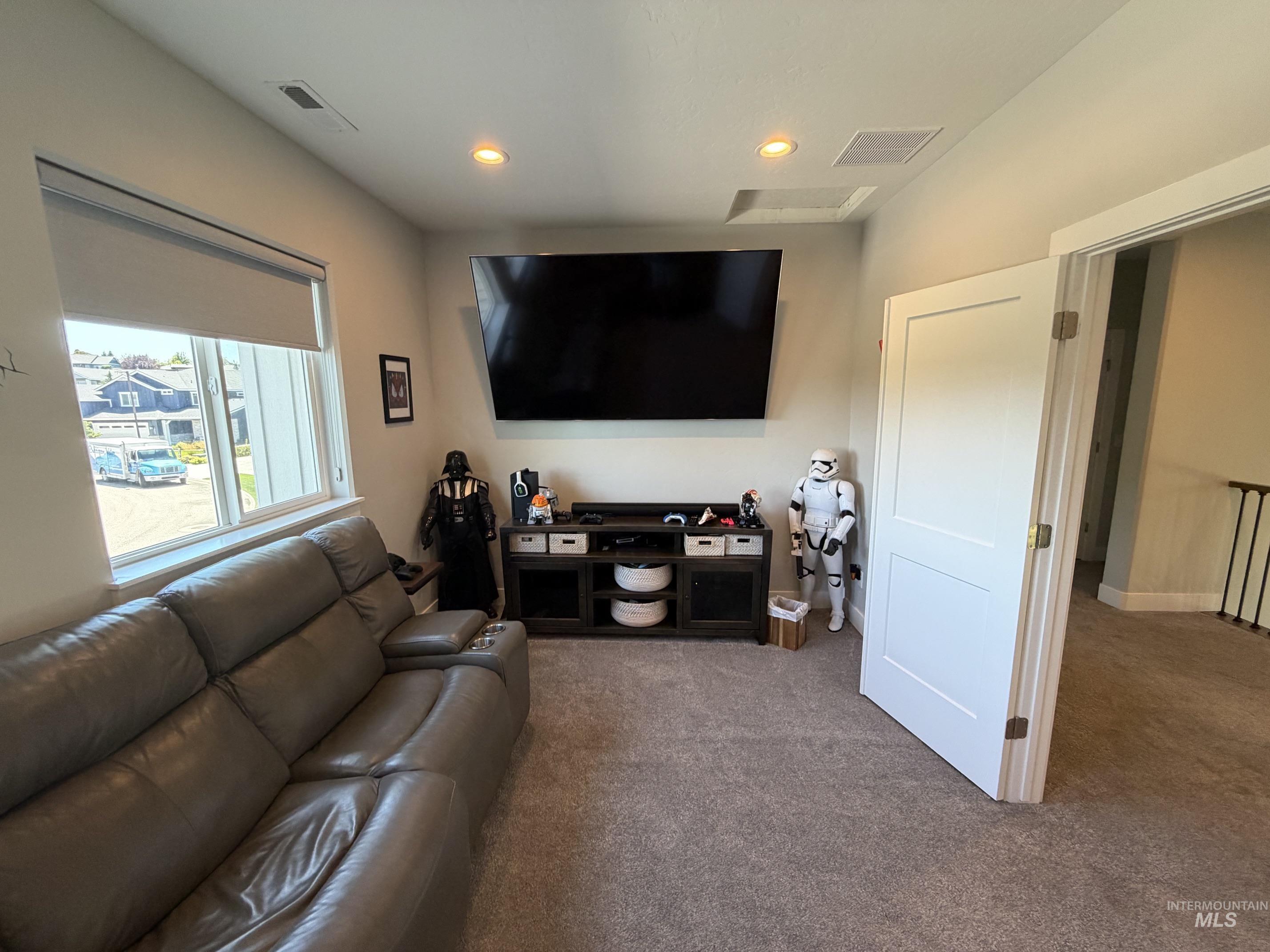Carpeted bonus room featuring recessed lighting, a large window with roller shades, and a built-in media console with open shelving