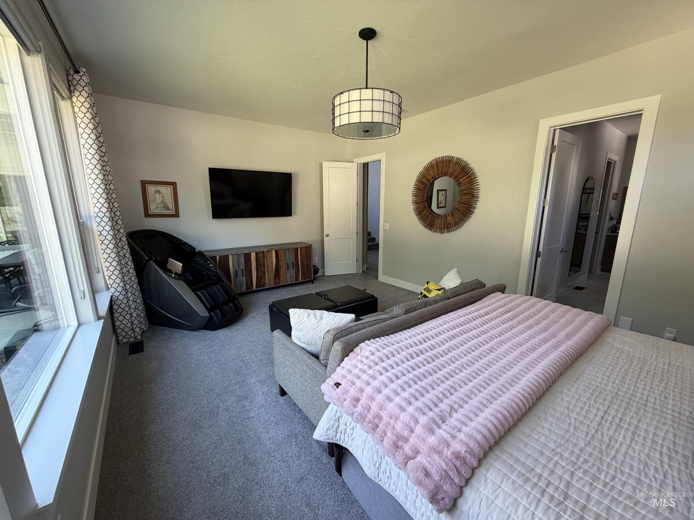Carpeted interior space featuring a large window, a built-in media console, and a contemporary ceiling light fixture