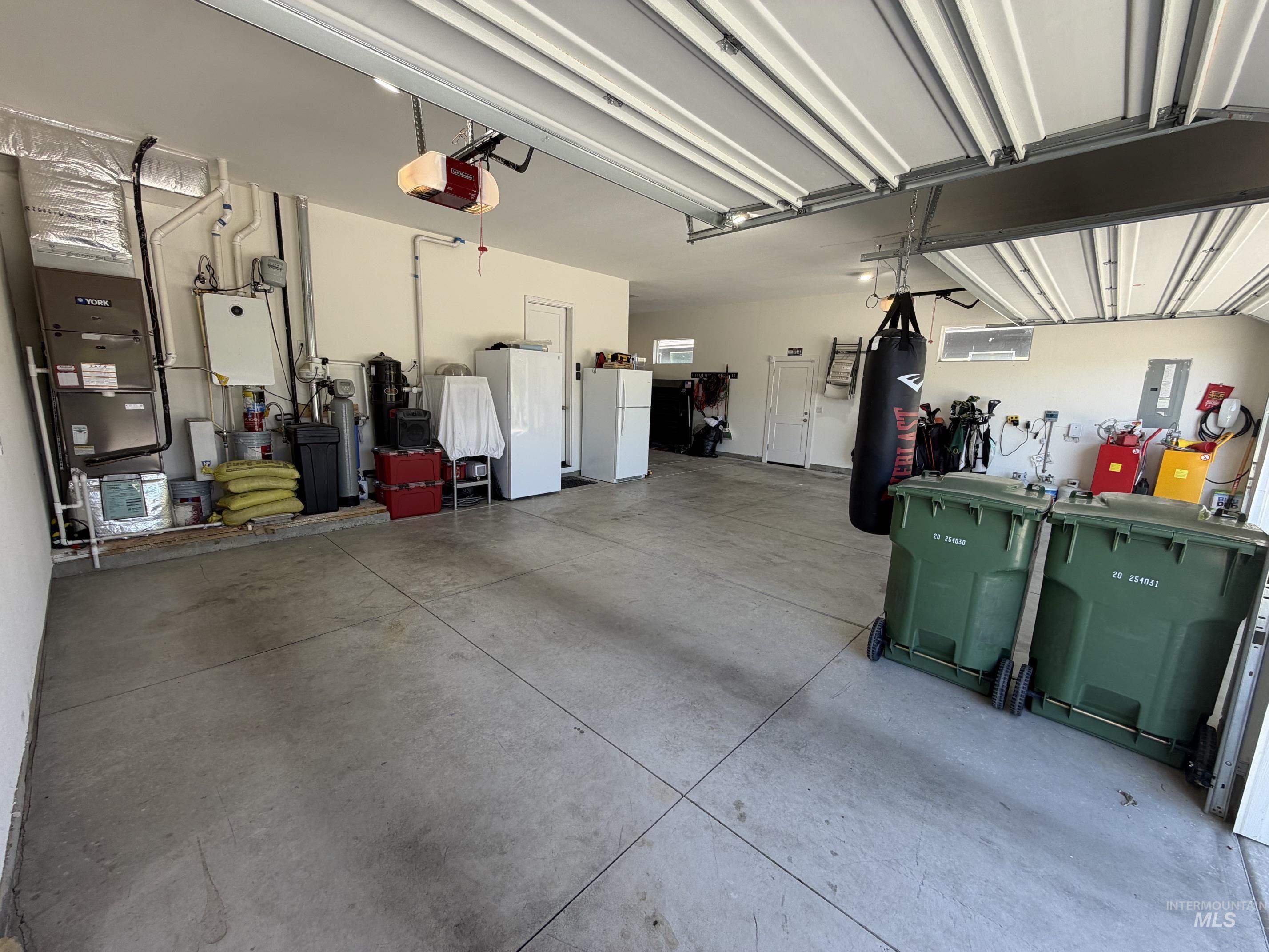 Spacious garage featuring a concrete floor, overhead garage door with opener, and utility access