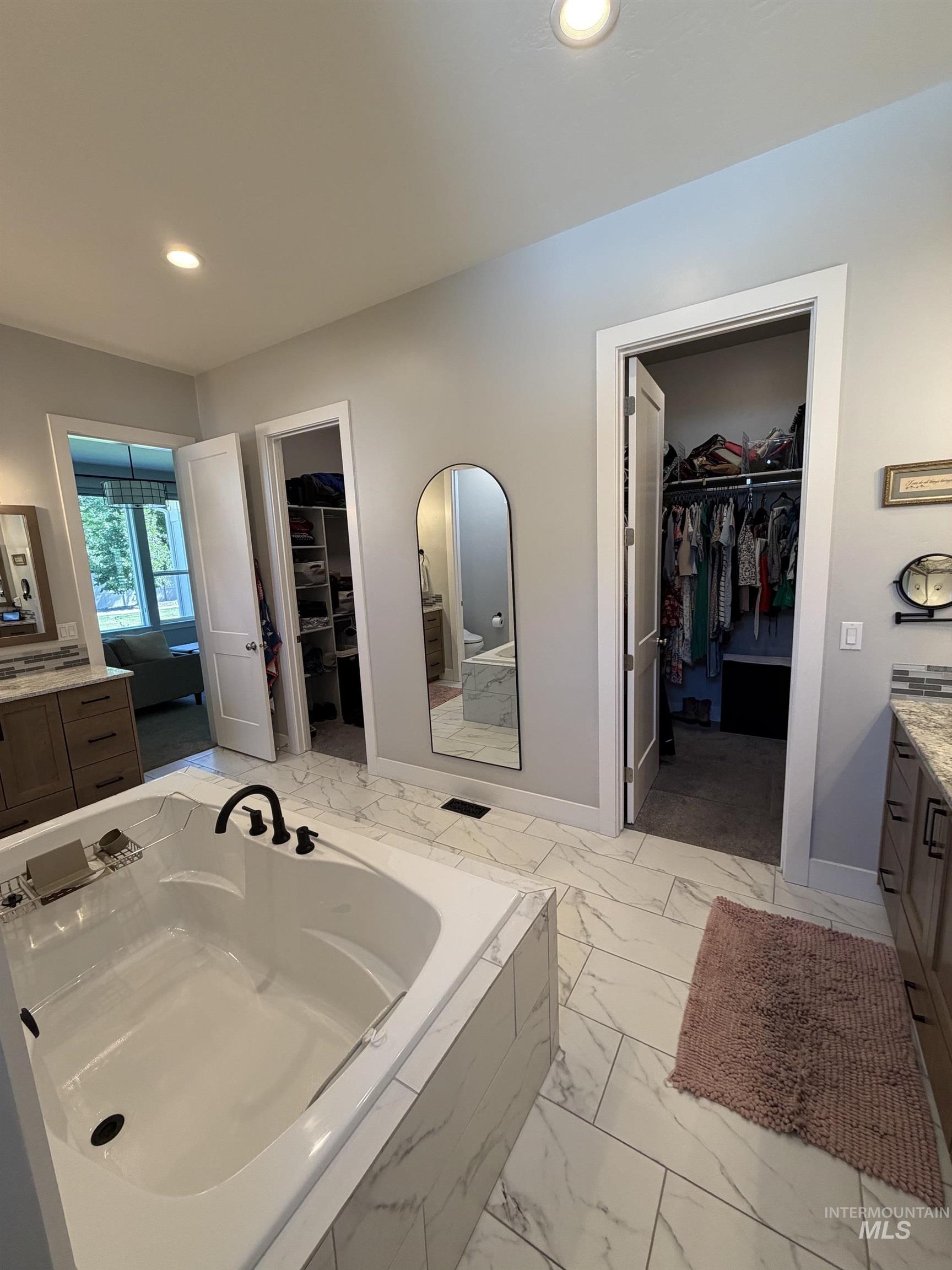 Soaking tub with matte black fixtures, set on large format tile flooring