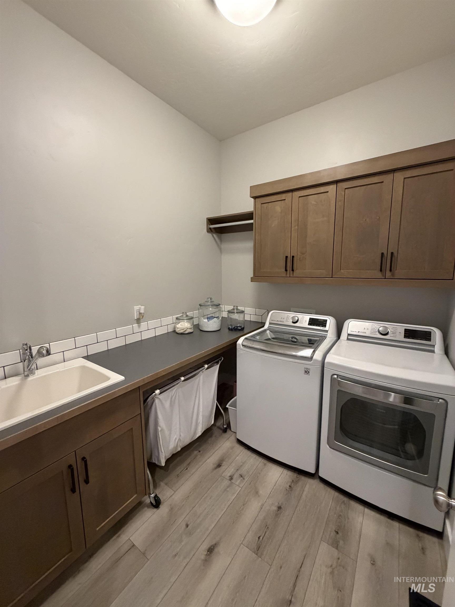 Dedicated laundry room featuring wood-finish flooring