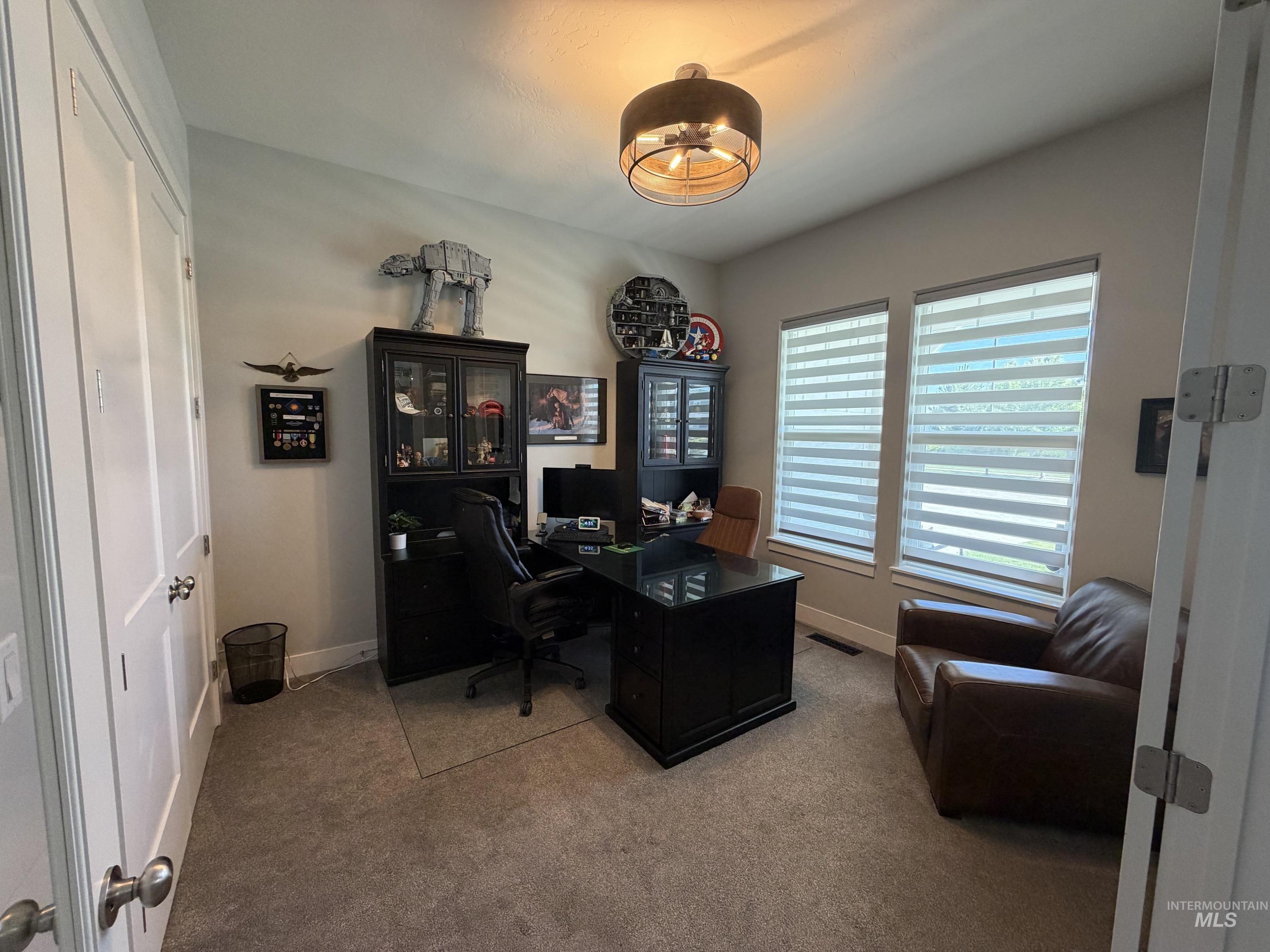 Carpeted room featuring a ceiling-mounted light fixture, two windows with horizontal blinds, and white doors
