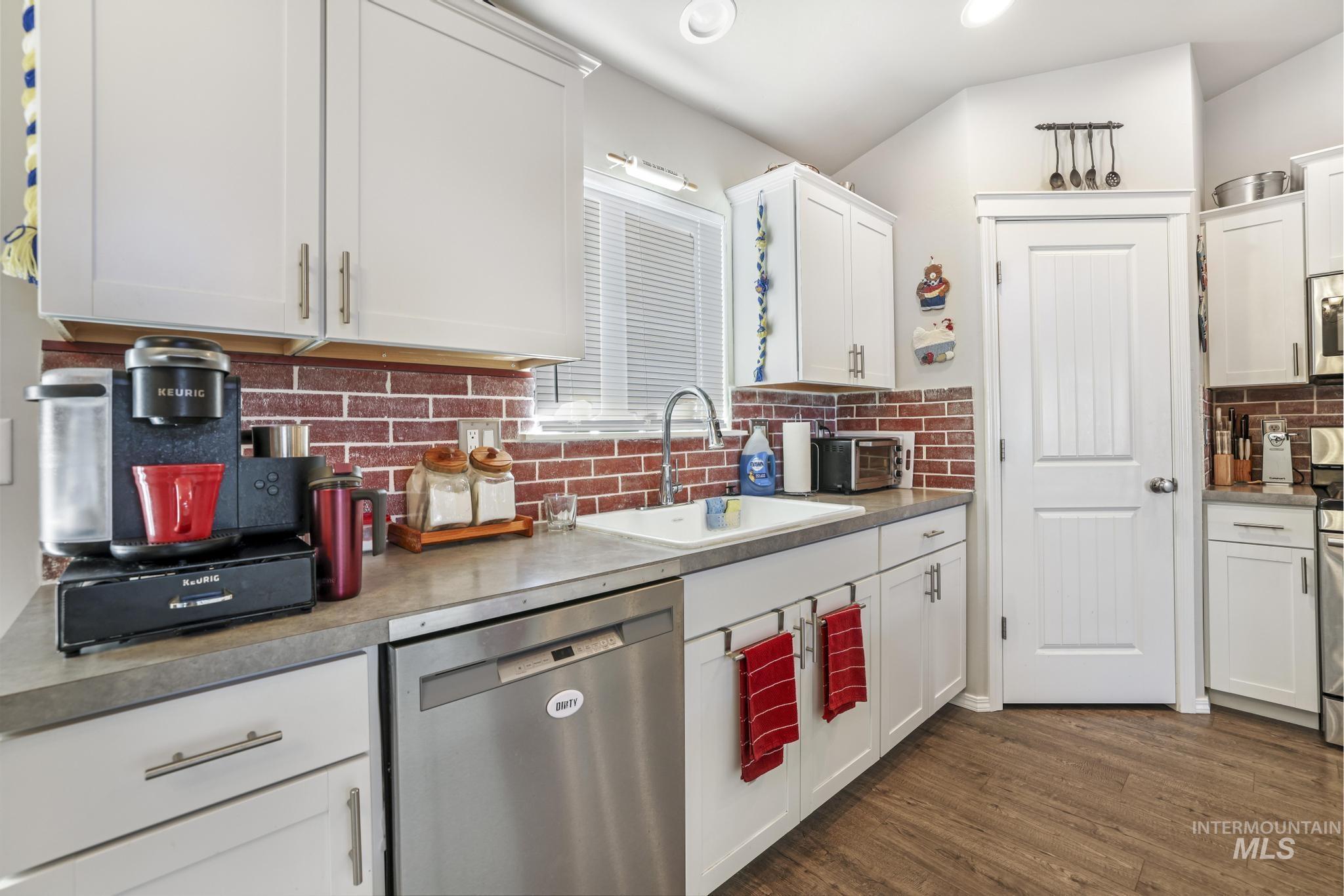 Kitchen with appliances with stainless steel finishes, white cabinetry, tasteful backsplash, dark wood-style flooring, and recessed lighting