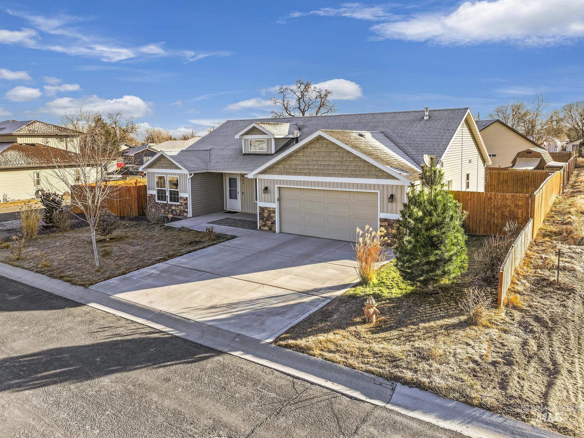 View of front of property featuring stone siding, concrete driveway, a garage, and roof with shingles