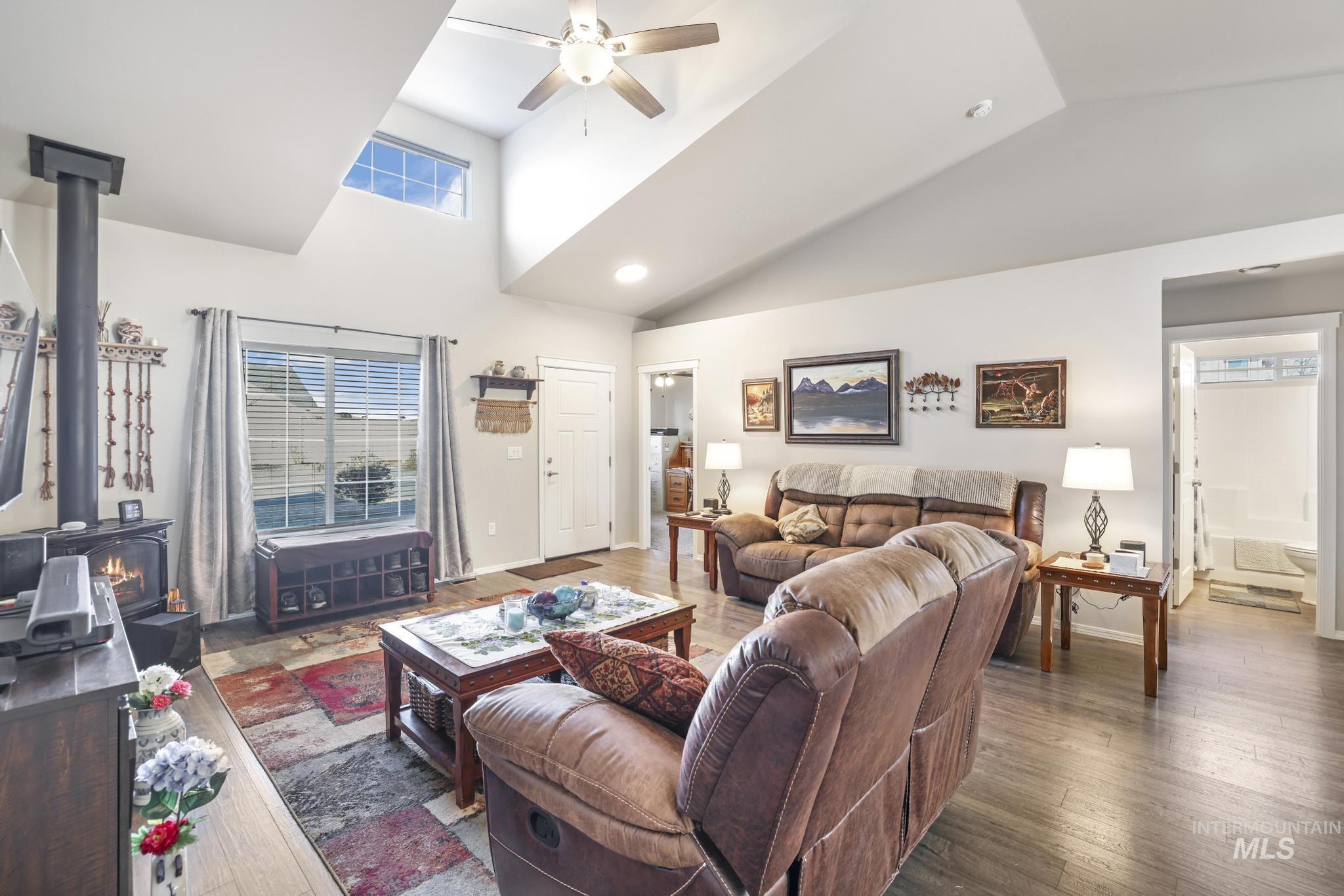 Living area featuring a wood stove, hardwood / wood-style flooring, high vaulted ceiling, and ceiling fan