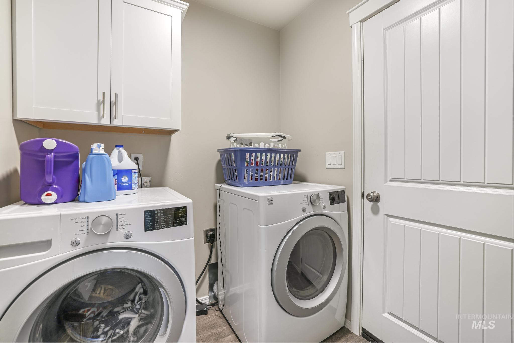 Laundry room featuring cabinet space, washer and clothes dryer, and light wood finished floors