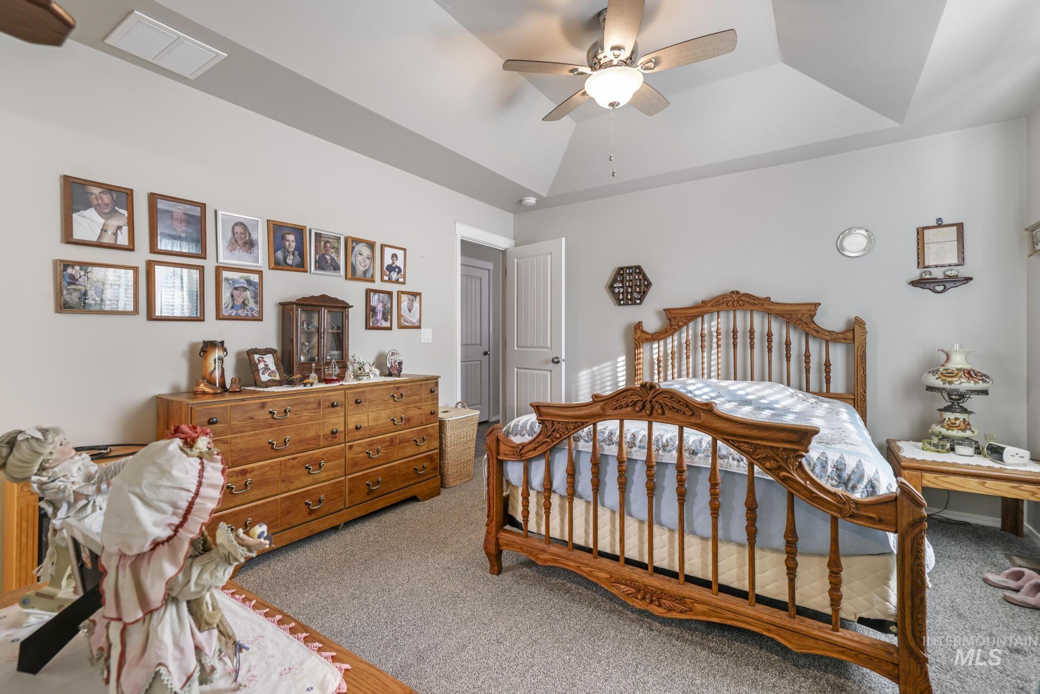 Carpeted bedroom featuring a tray ceiling and ceiling fan