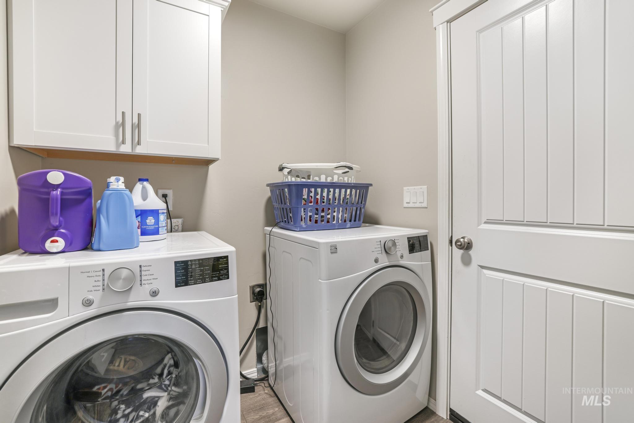 Laundry room with cabinet space, washer and dryer, and wood finished floors
