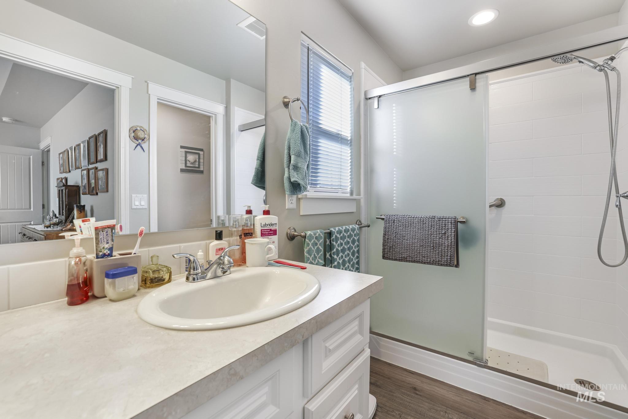 Bathroom featuring a shower stall, vanity, and dark wood-style floors