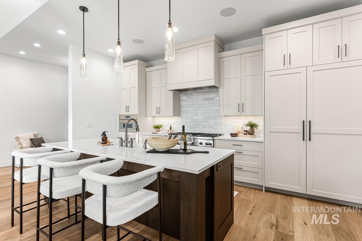 Kitchen with light wood-style floors, dark brown cabinets, a breakfast bar, decorative light fixtures, and recessed lighting