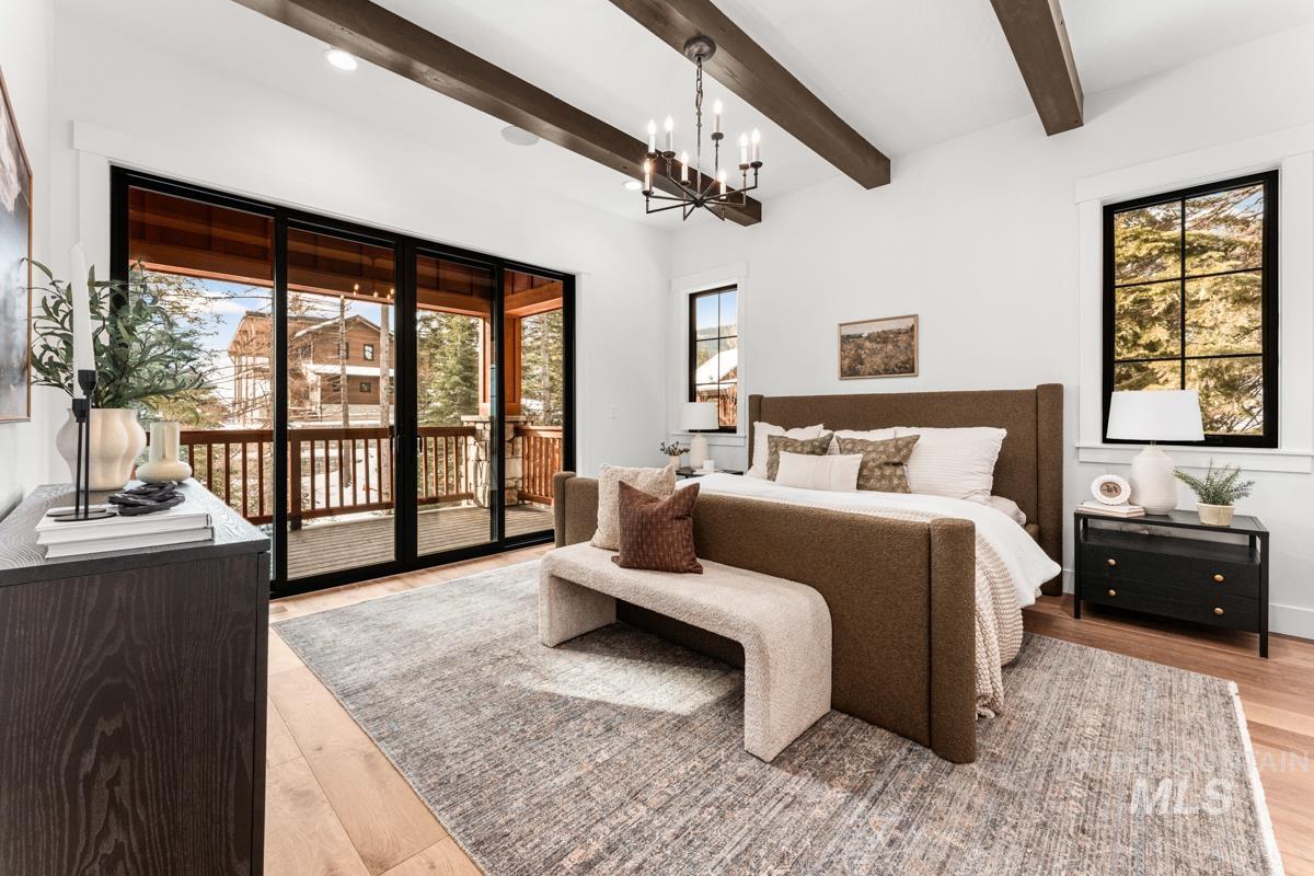 Bedroom featuring access to exterior, light wood-style floors, beamed ceiling, and a chandelier