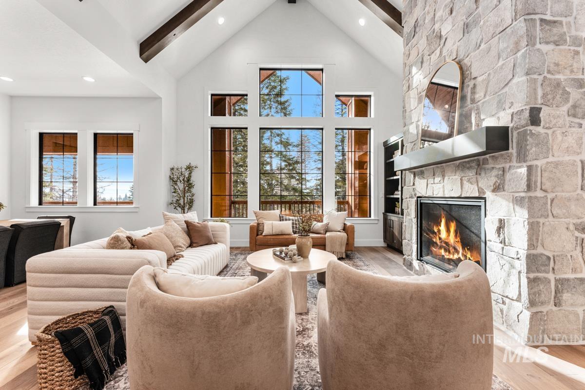 Living room featuring wood finished floors, beamed ceiling, high vaulted ceiling, a fireplace, and recessed lighting
