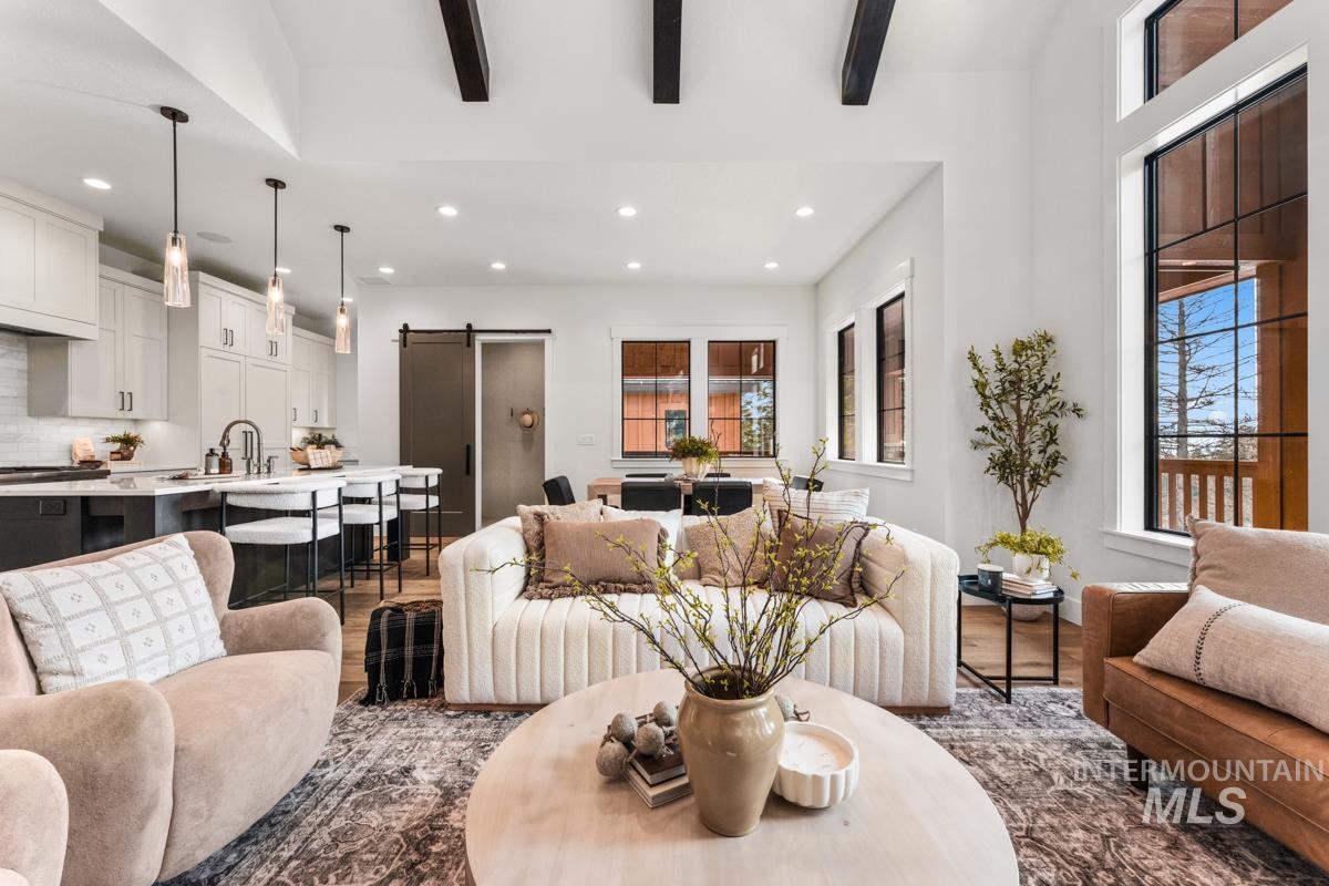 Living area featuring a barn door, beamed ceiling, dark wood finished floors, and recessed lighting