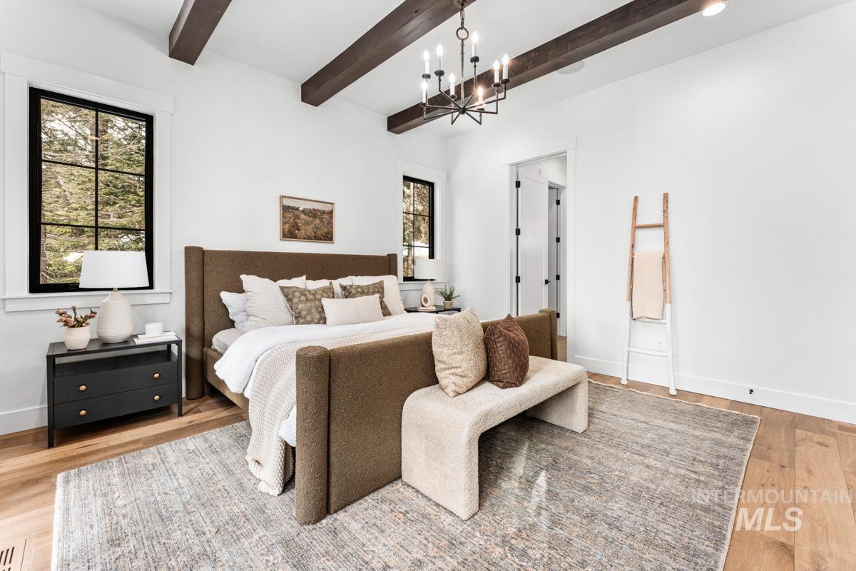 Bedroom with light wood-type flooring, beamed ceiling, and a chandelier