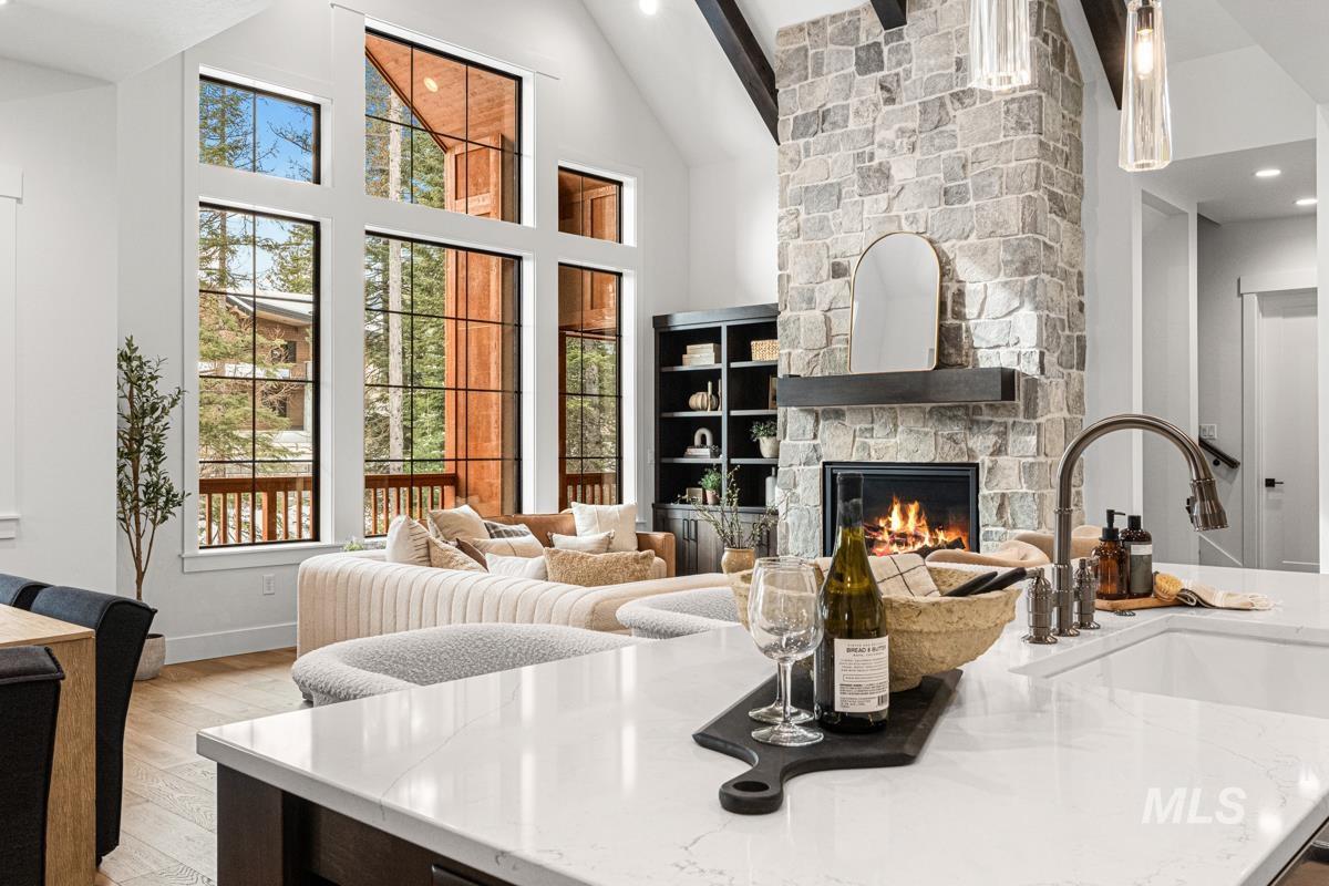 Living room featuring a stone fireplace, recessed lighting, high vaulted ceiling, and light wood-style flooring