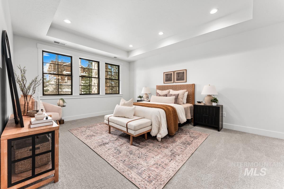 Bedroom featuring light colored carpet, a tray ceiling, and recessed lighting