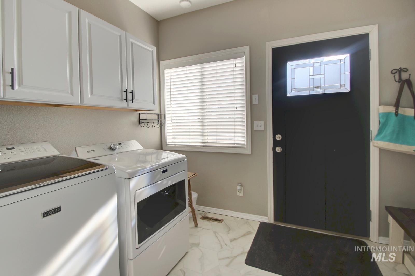 Laundry room featuring light marble finish flooring, washer and dryer, and cabinet space