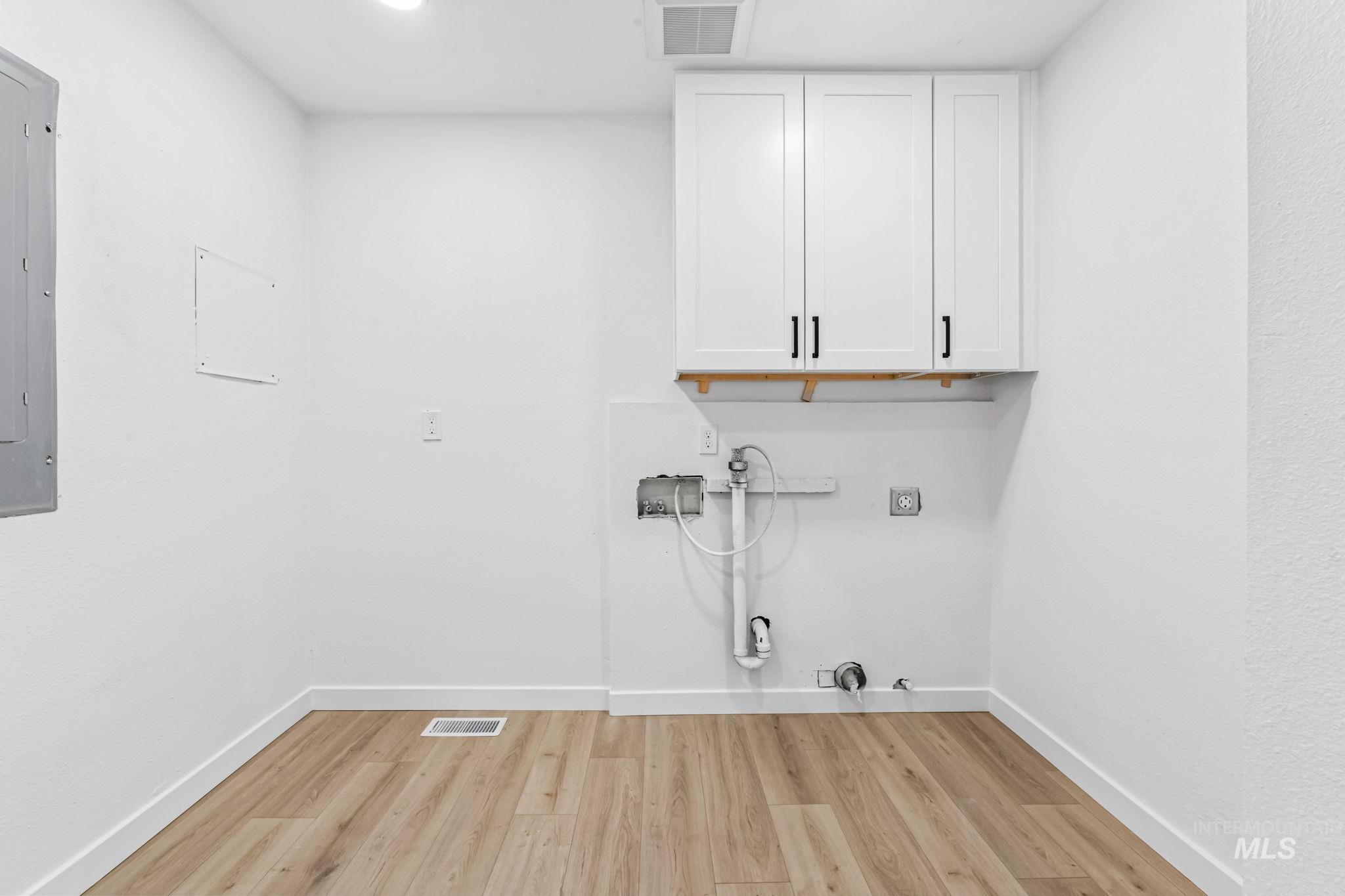 Laundry room with cabinet space, hookup for a gas dryer, light wood finished floors, hookup for a washing machine, and electric dryer hookup