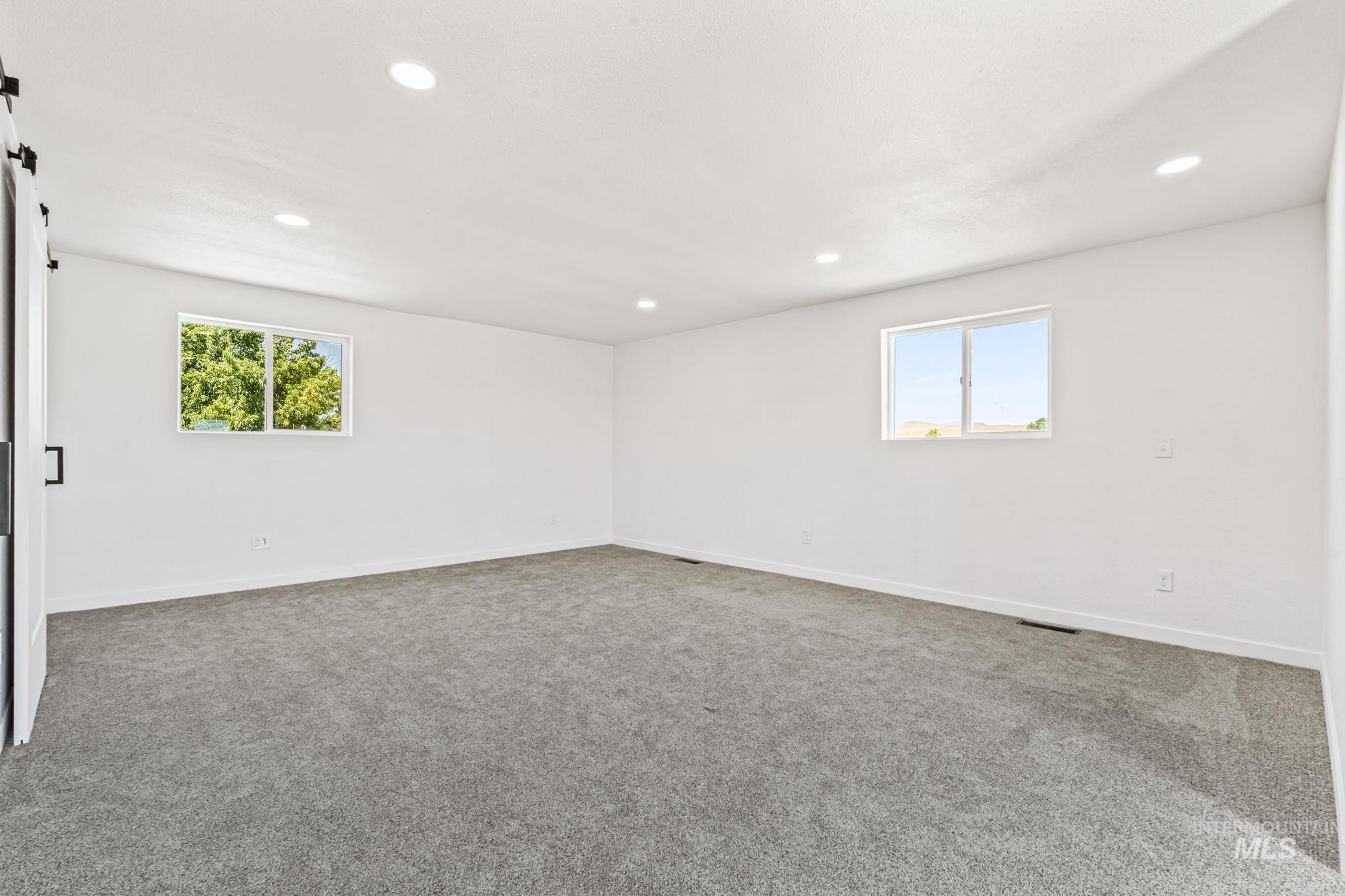 Carpeted empty room with a barn door and recessed lighting