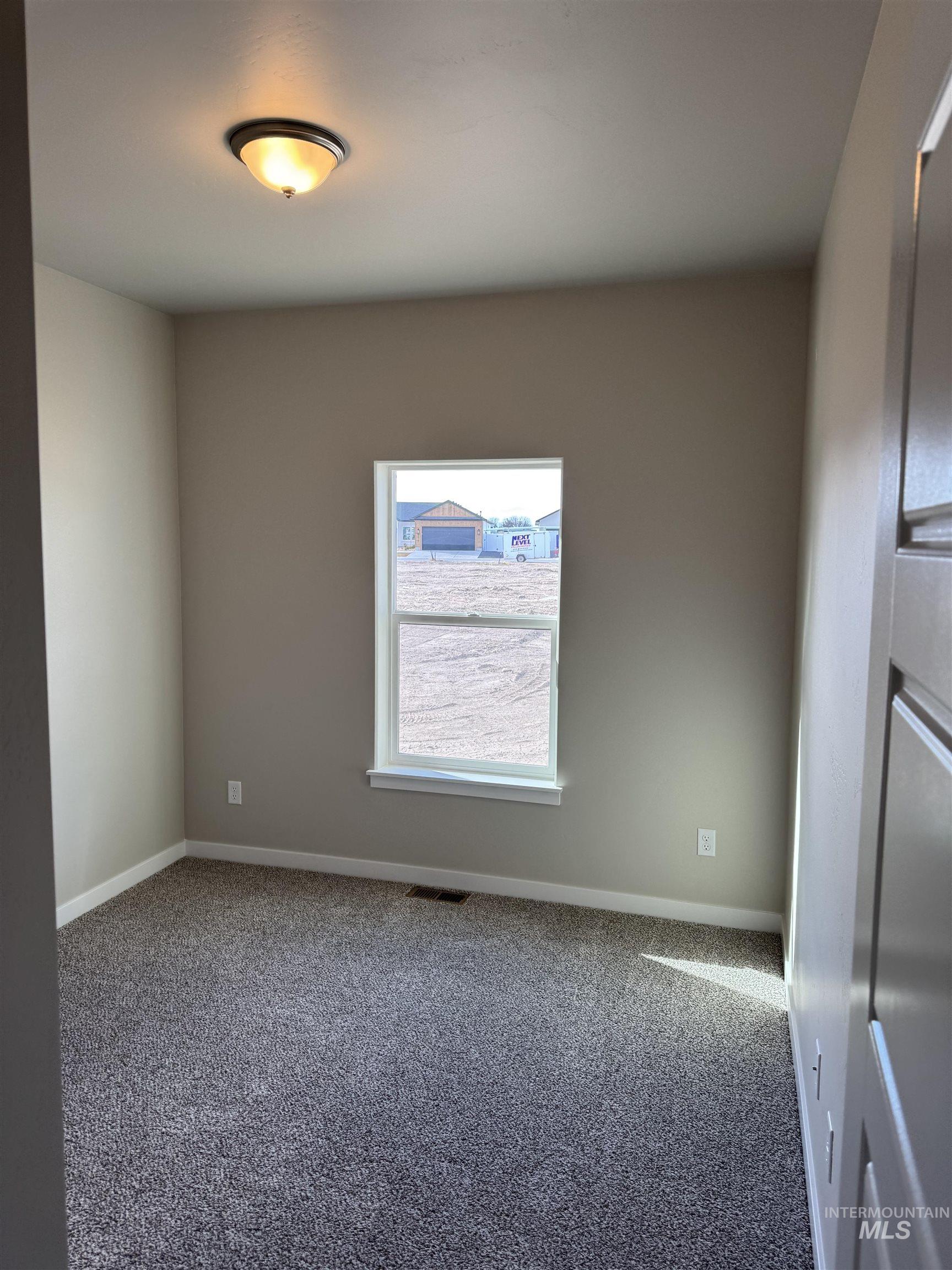Carpeted spare room featuring baseboards