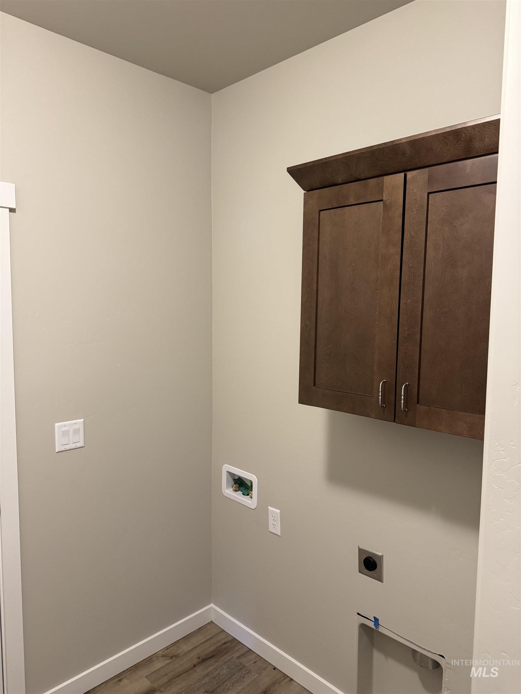 Laundry room with wood finished floors, cabinet space, hookup for an electric dryer, and washer hookup