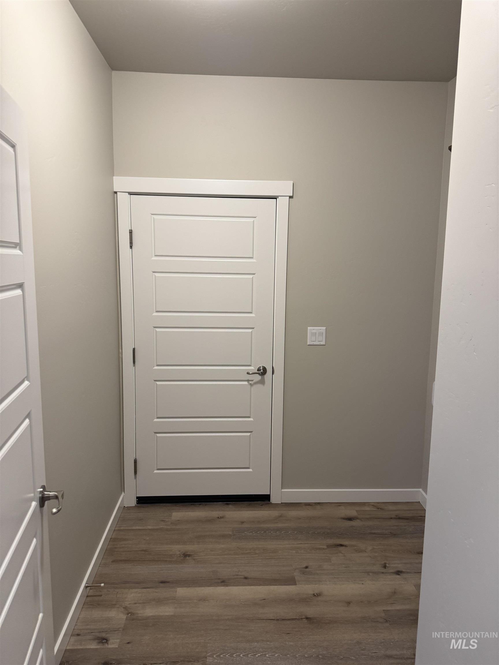 Doorway with wood finished floors and baseboards
