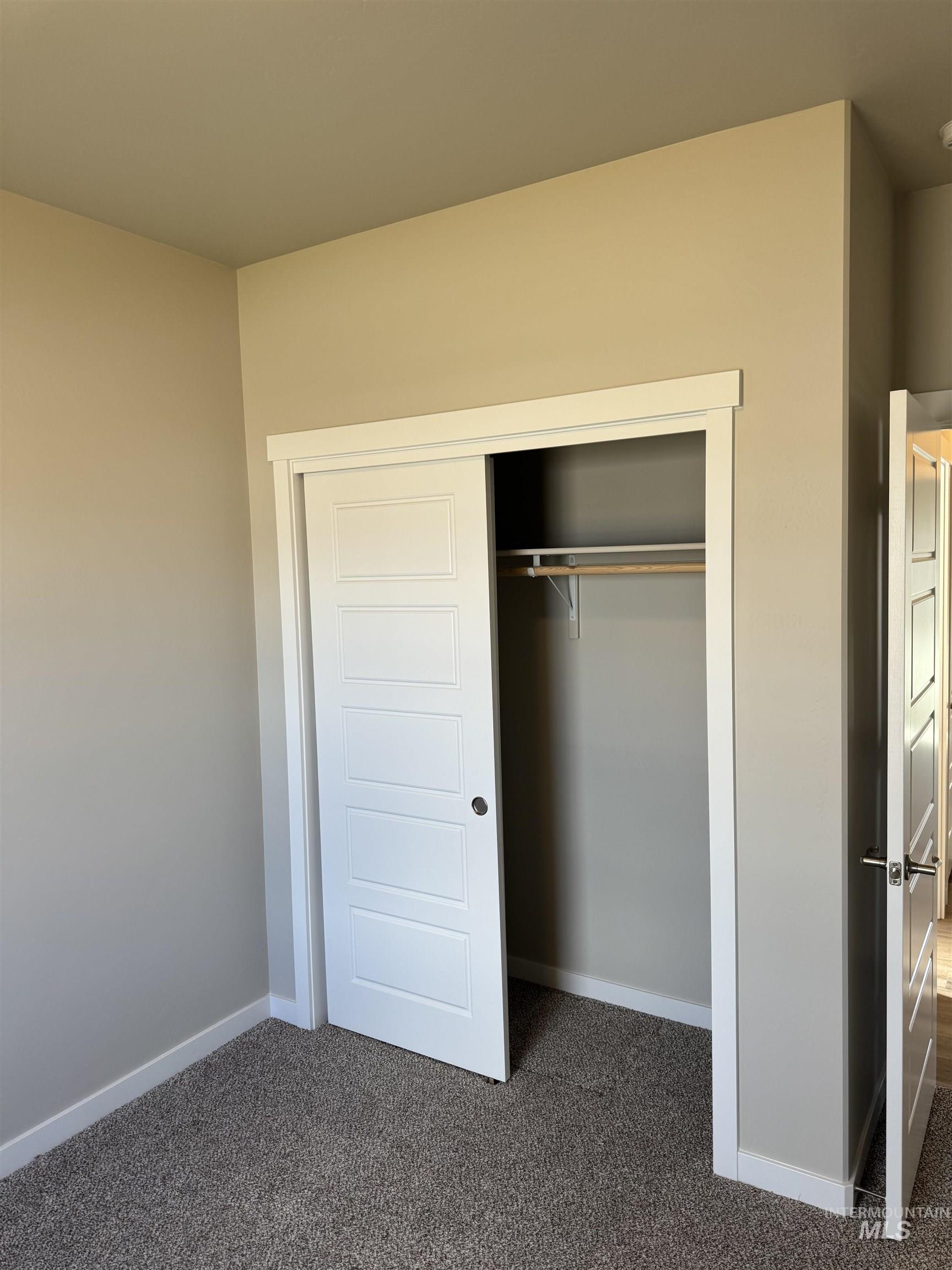 Unfurnished bedroom featuring dark carpet and a closet