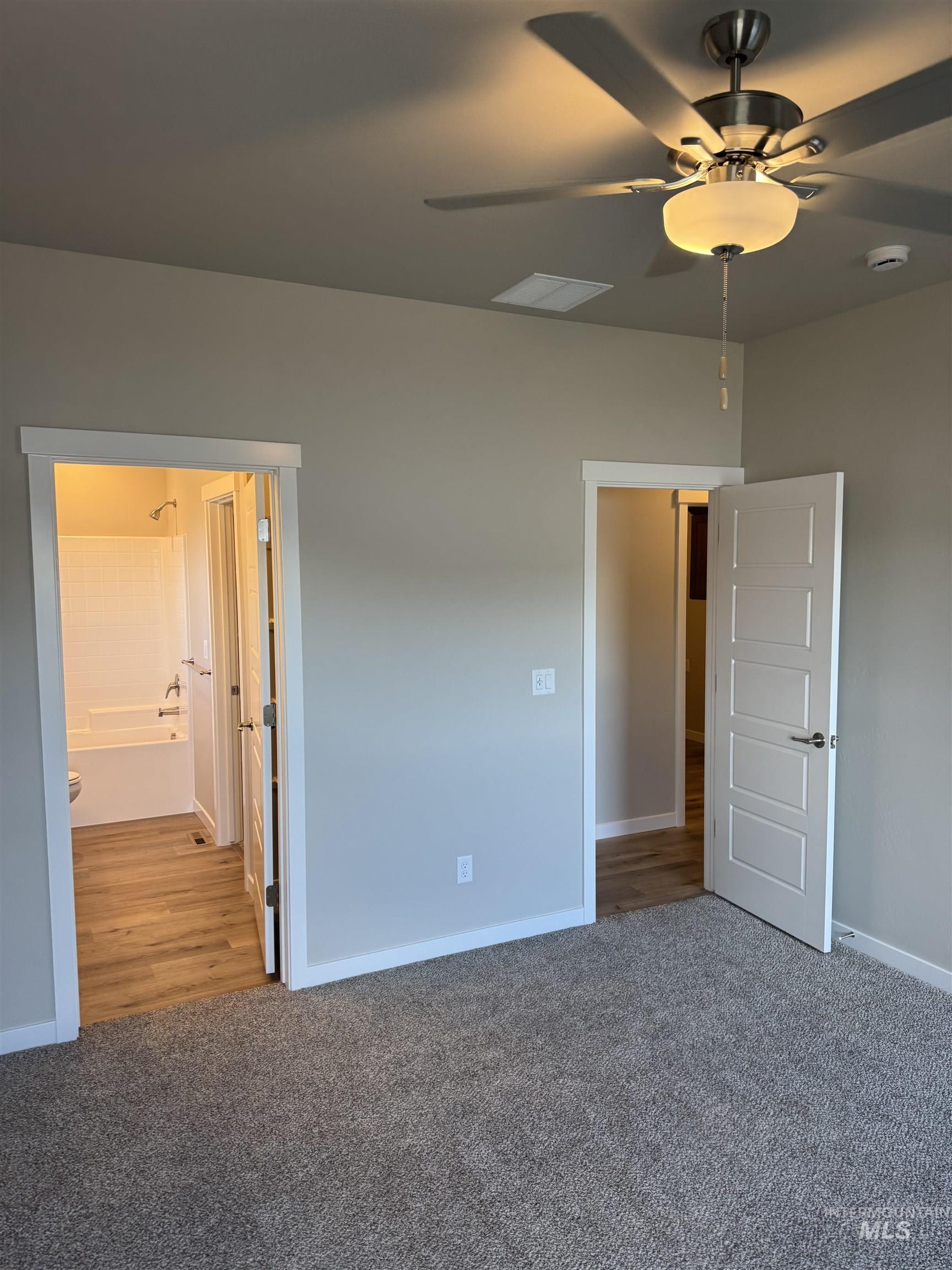 Unfurnished bedroom with light colored carpet, a ceiling fan, and connected bathroom