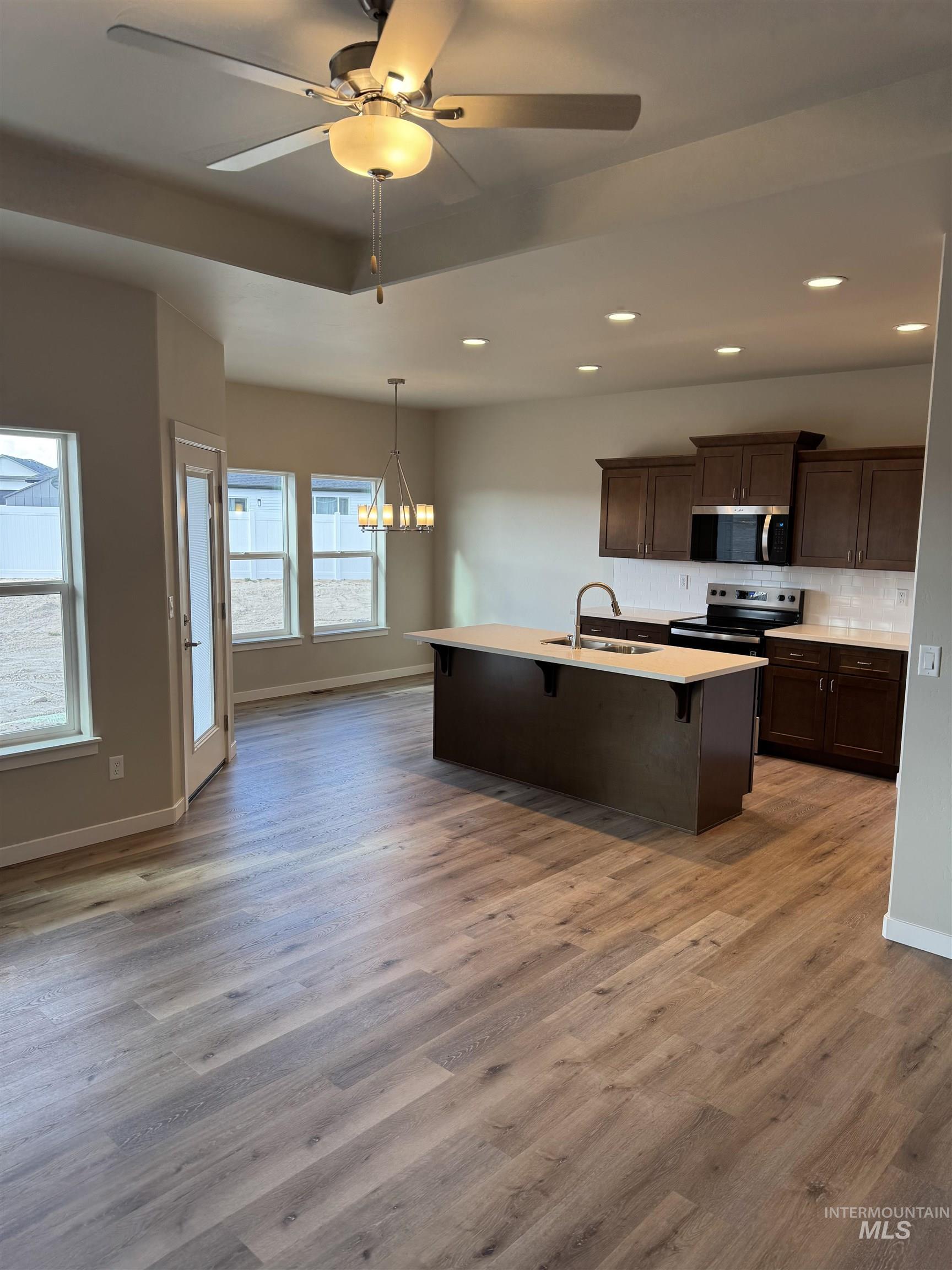 Kitchen with a kitchen bar, a ceiling fan, a chandelier, stainless steel appliances, and dark wood finish cabinets