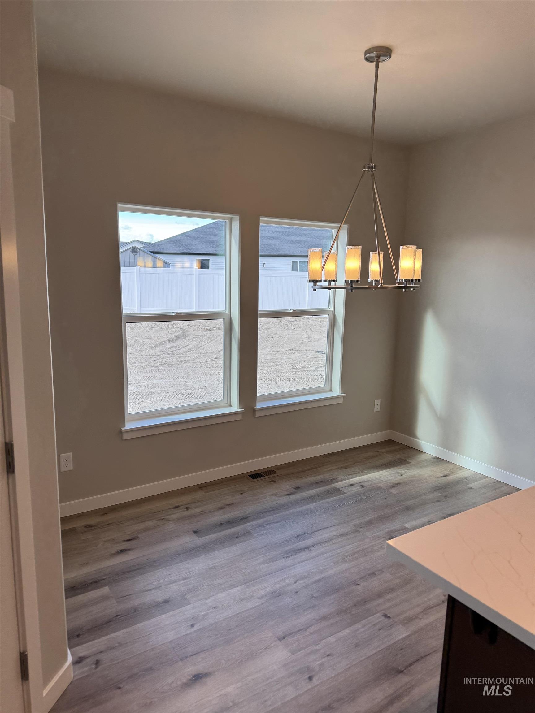 Unfurnished dining area with suspended lighting and light wood-type flooring