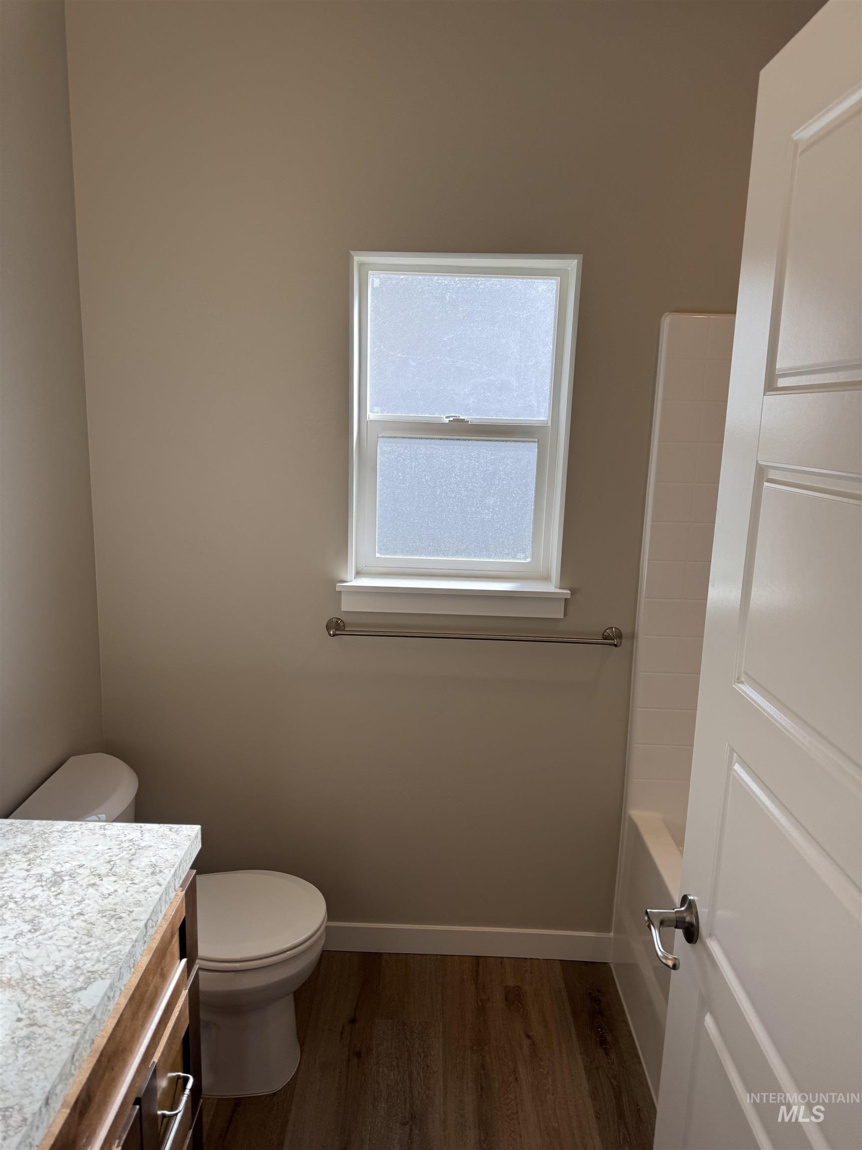 Bathroom featuring vanity, dark wood finished floors, and tub / shower combination