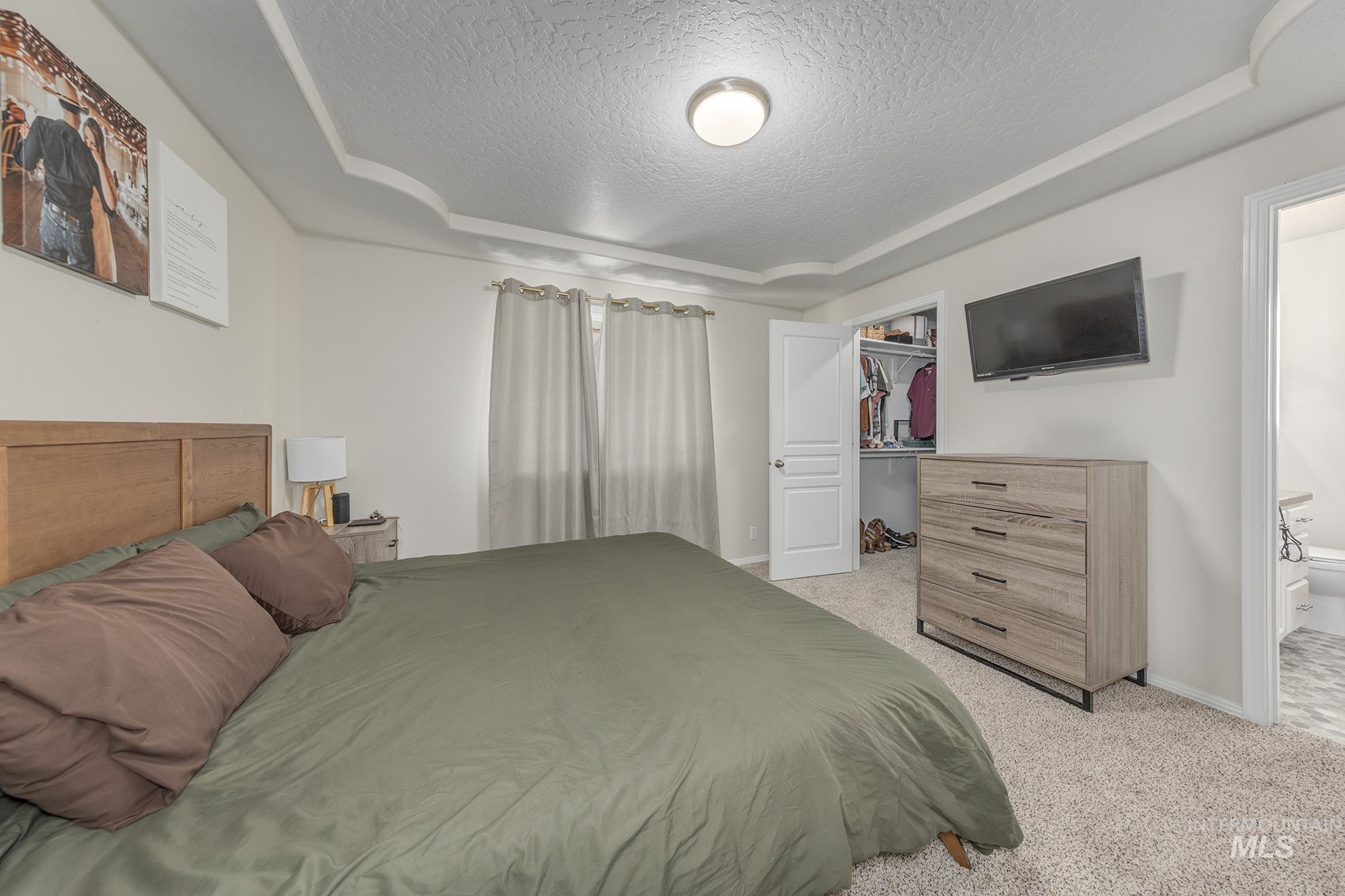 Bedroom featuring a textured ceiling, light colored carpet, and a spacious closet