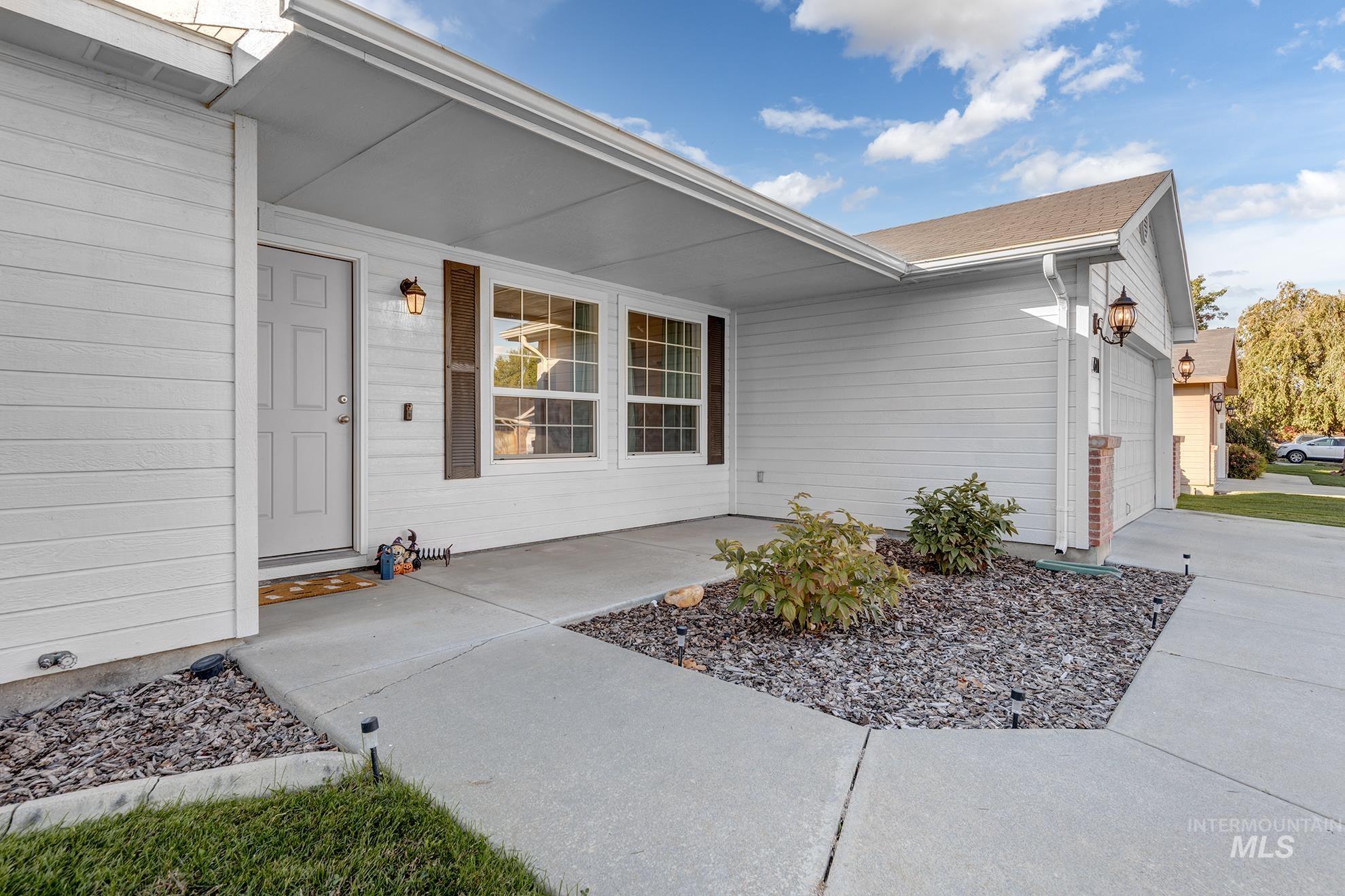 View of exterior entry with an attached garage, covered porch, and concrete driveway
