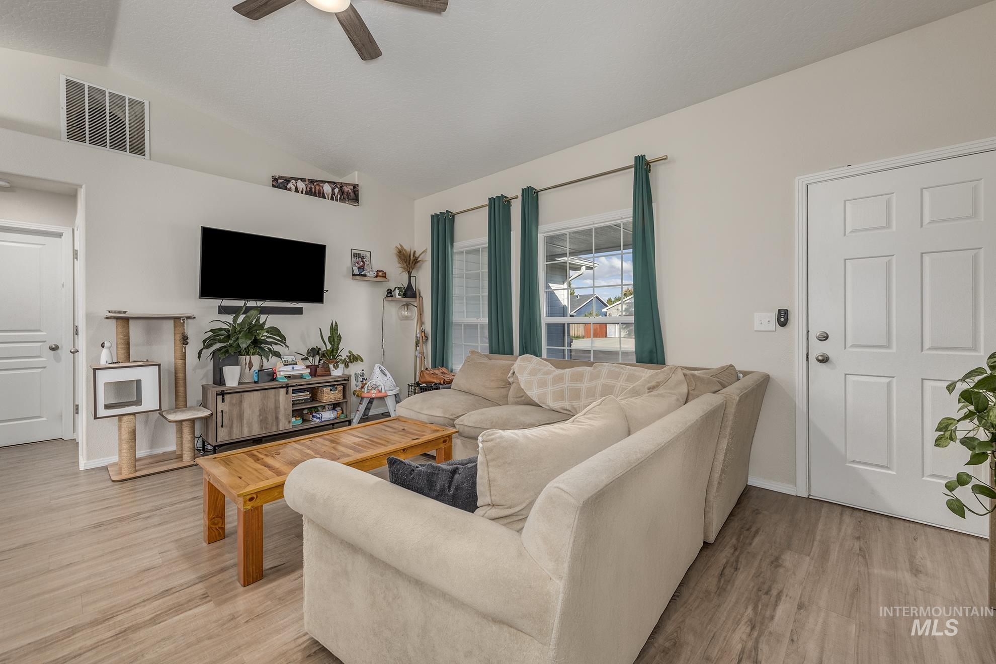 Living room featuring light wood-style floors, lofted ceiling, and ceiling fan