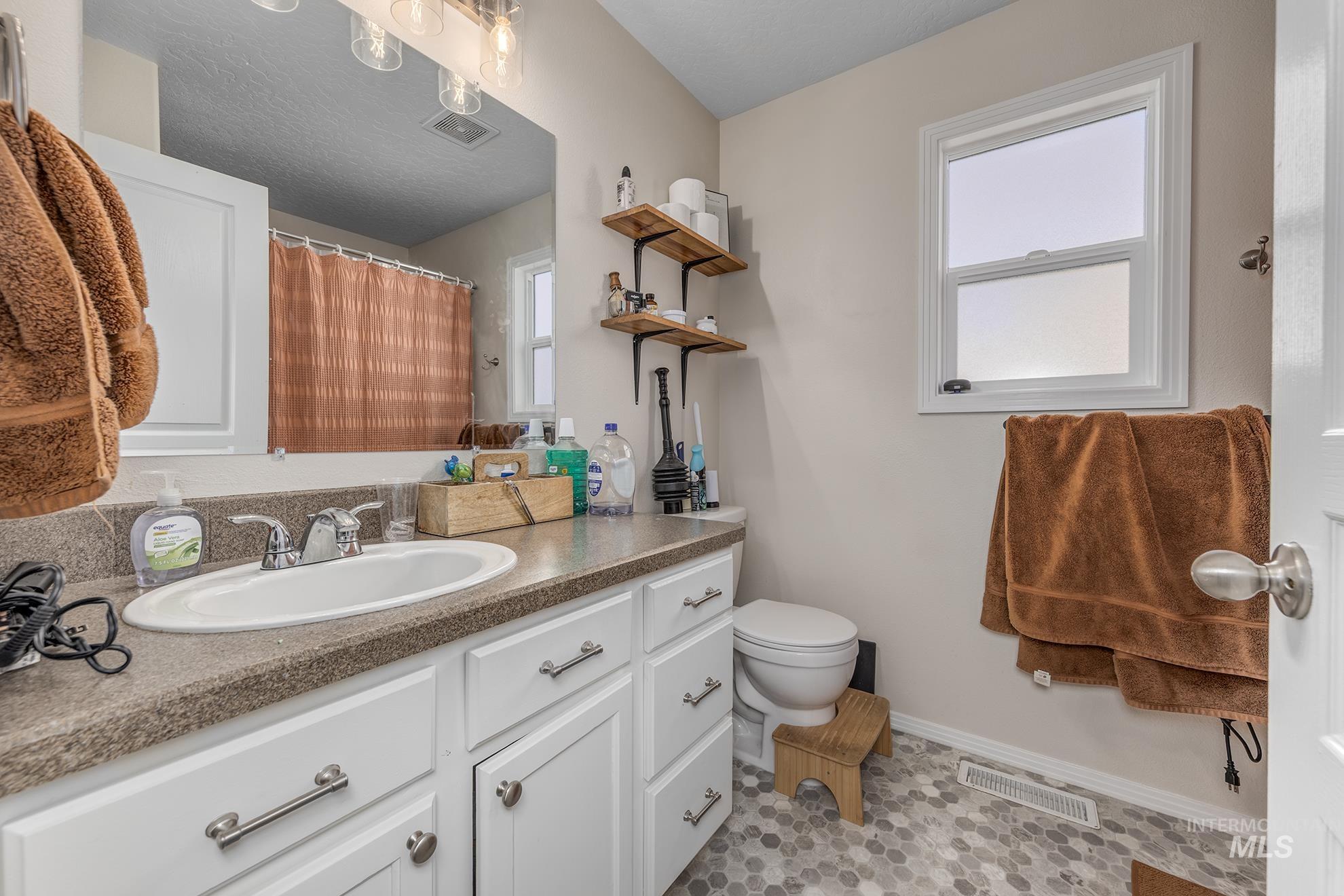 Full bath featuring vanity, light tile patterned floors, and a shower with curtain
