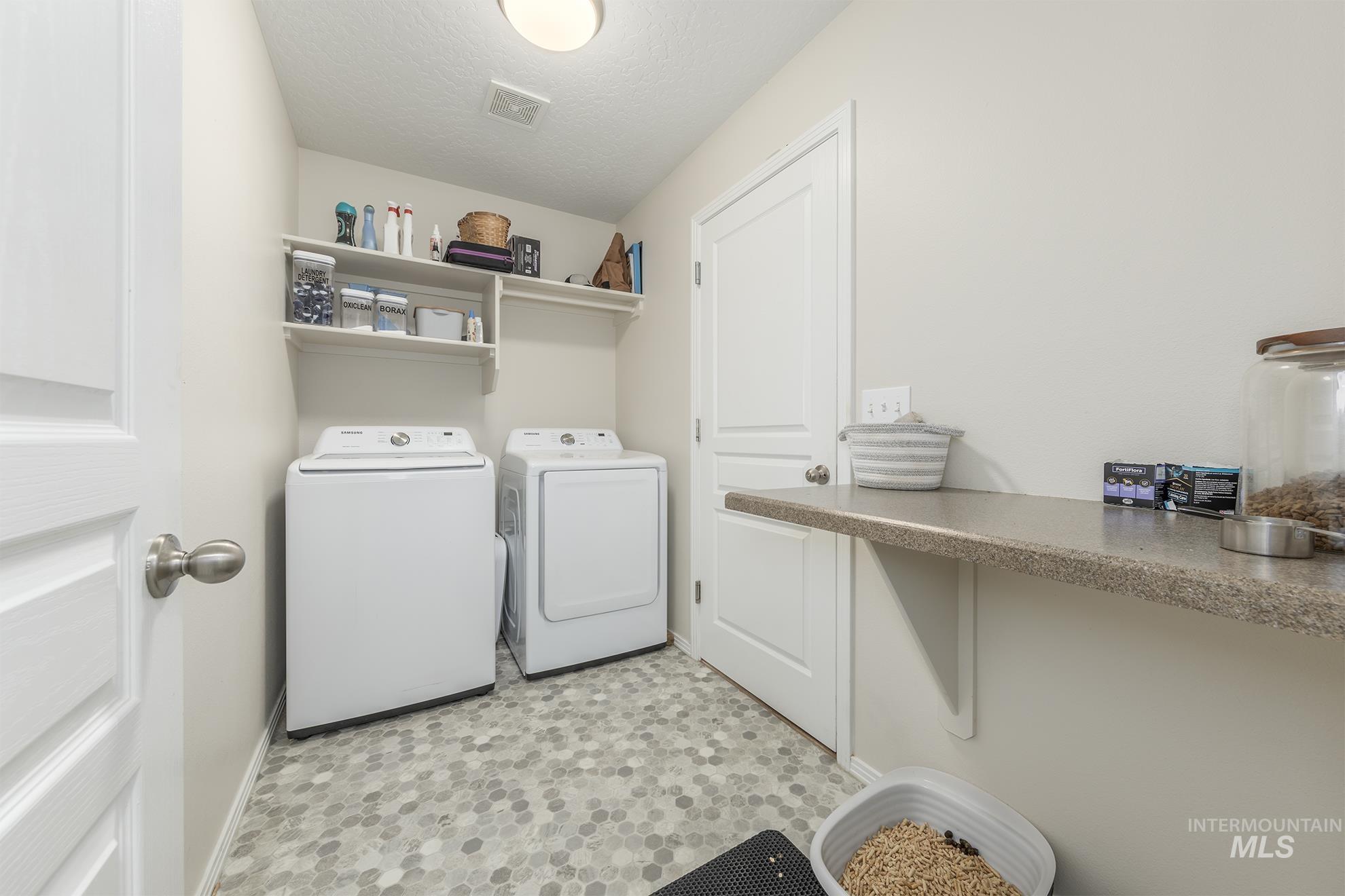 Washroom featuring washer and dryer and a textured ceiling