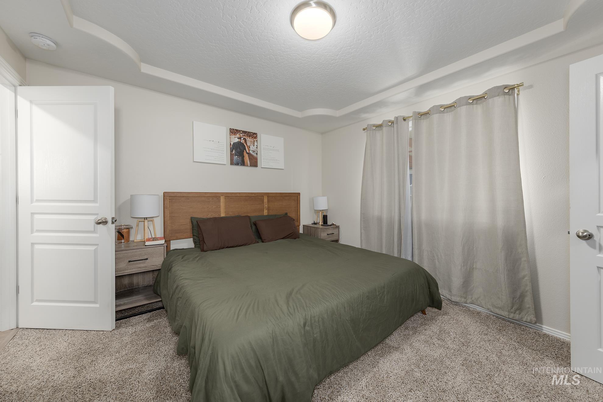 Carpeted bedroom with a textured ceiling and a tray ceiling