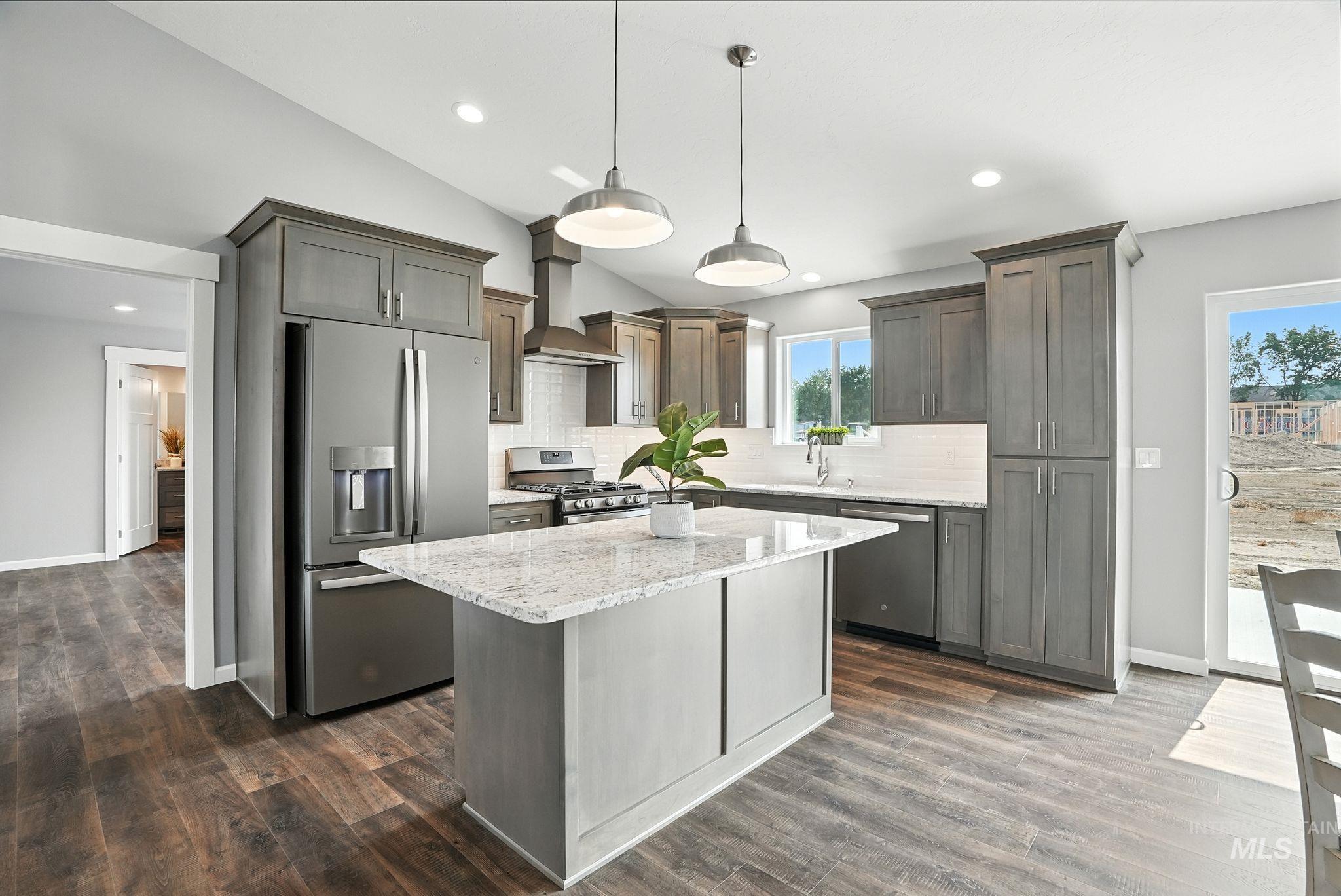 Kitchen with tasteful backsplash, stainless steel appliances, light stone countertops, a center island, and lofted ceiling