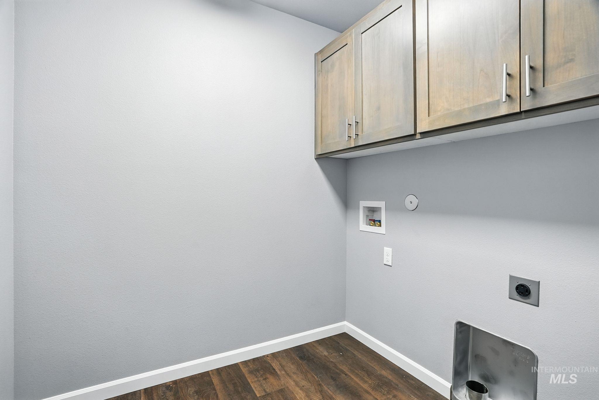 Washroom with dark wood finished floors, washer hookup, electric dryer hookup, cabinet space, and hookup for a gas dryer