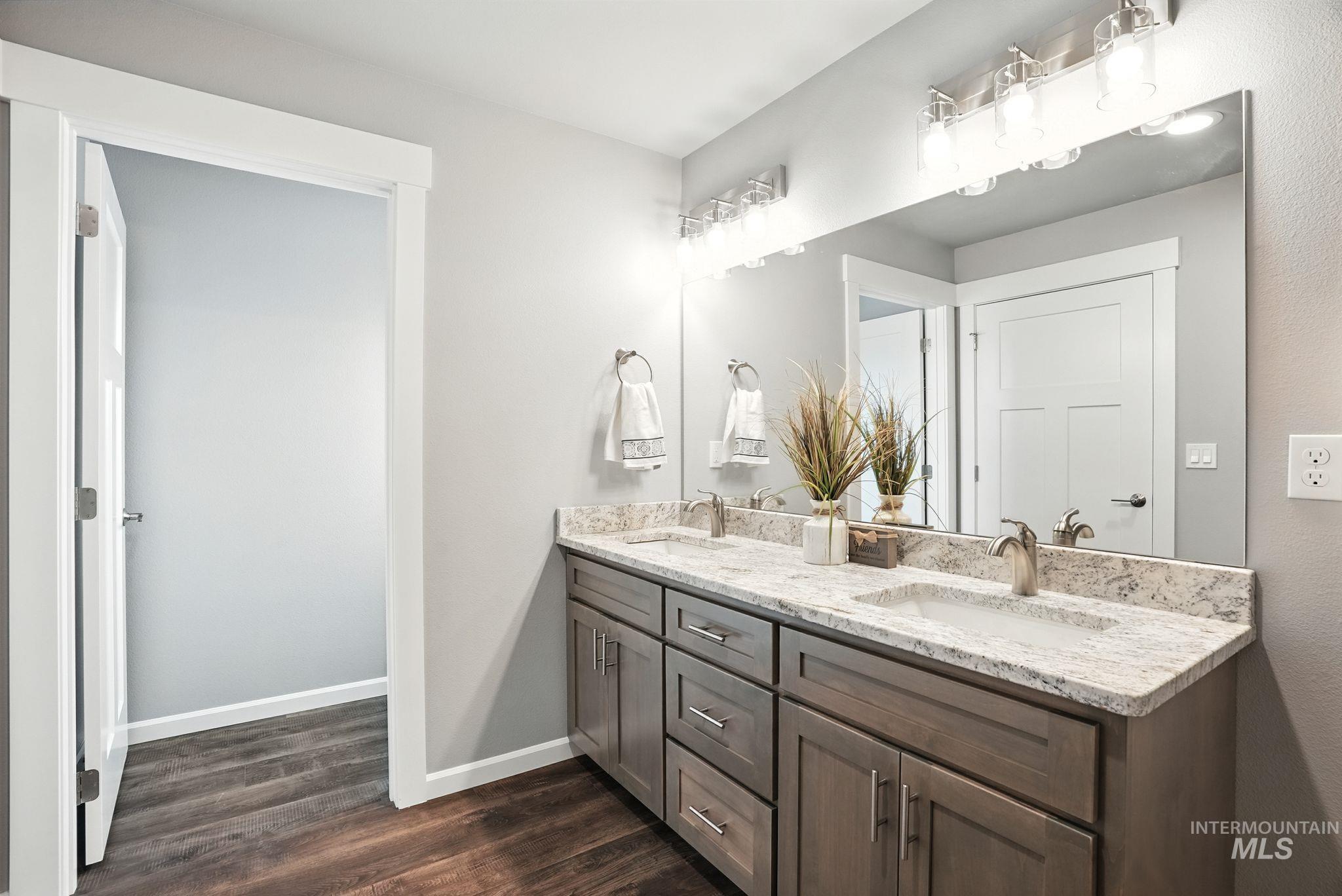 Bathroom with double vanity and dark wood-type flooring