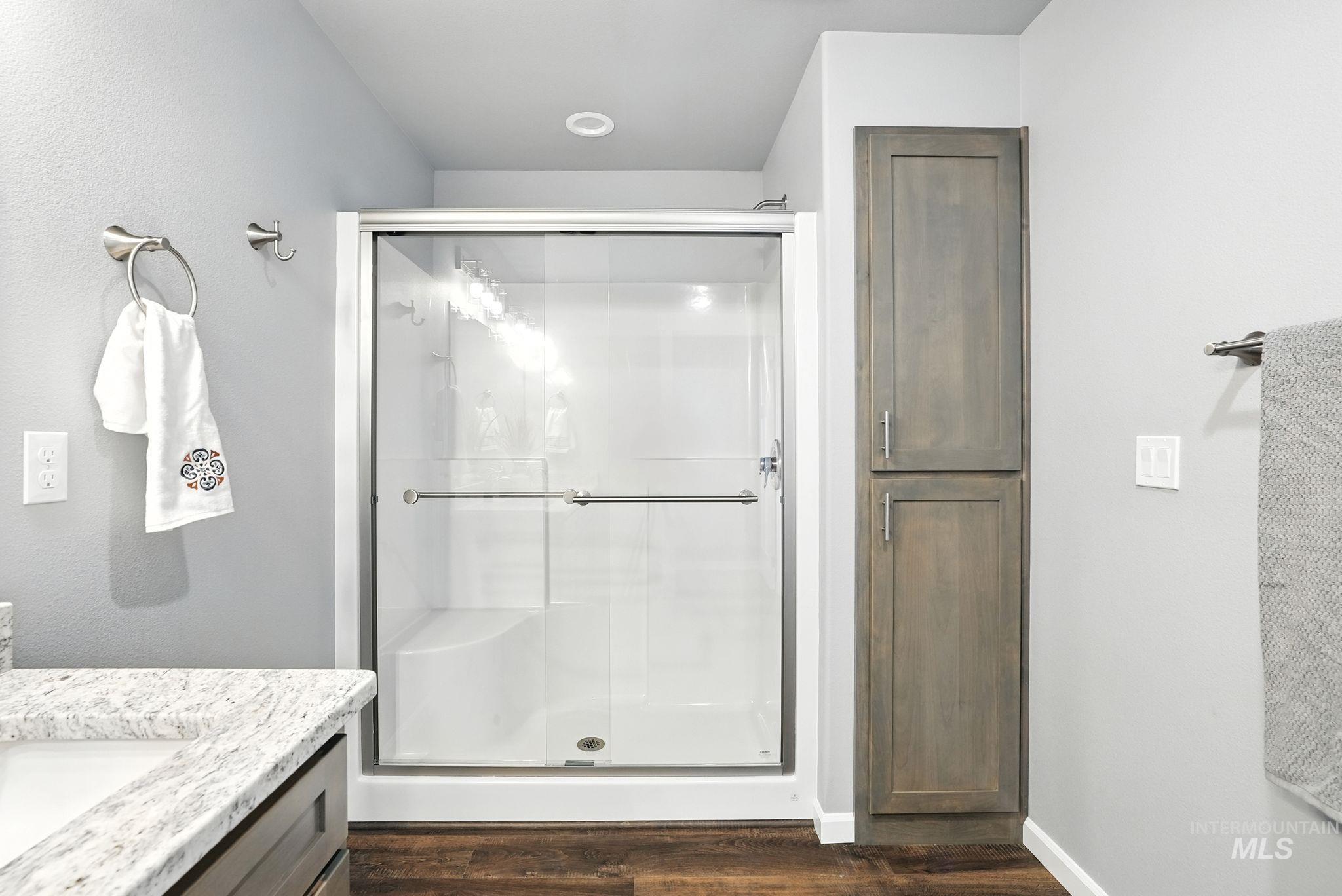 Full bath with a stall shower, vanity, and dark wood finished floors