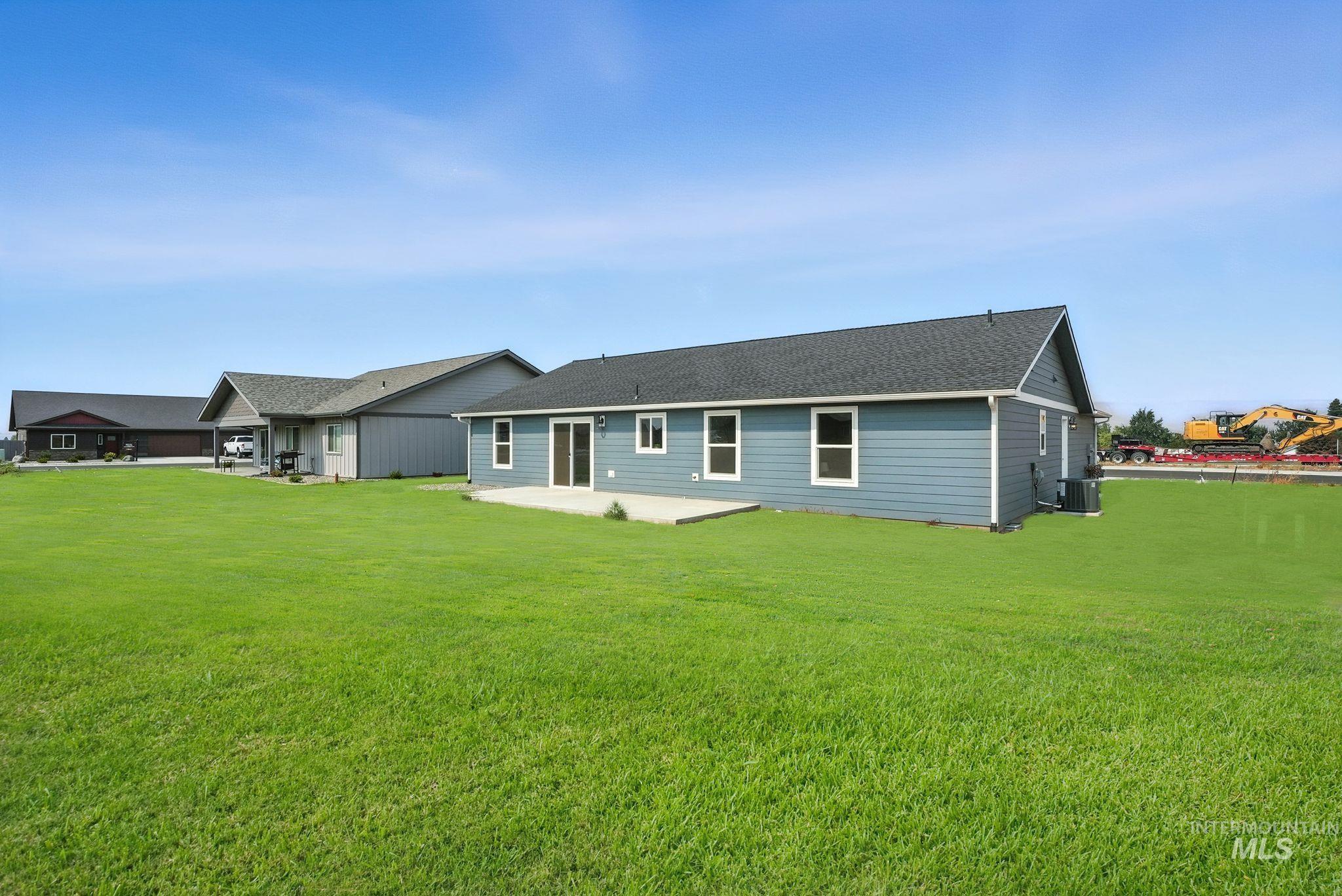Rear view of property featuring a patio area, a shingled roof, and a yard