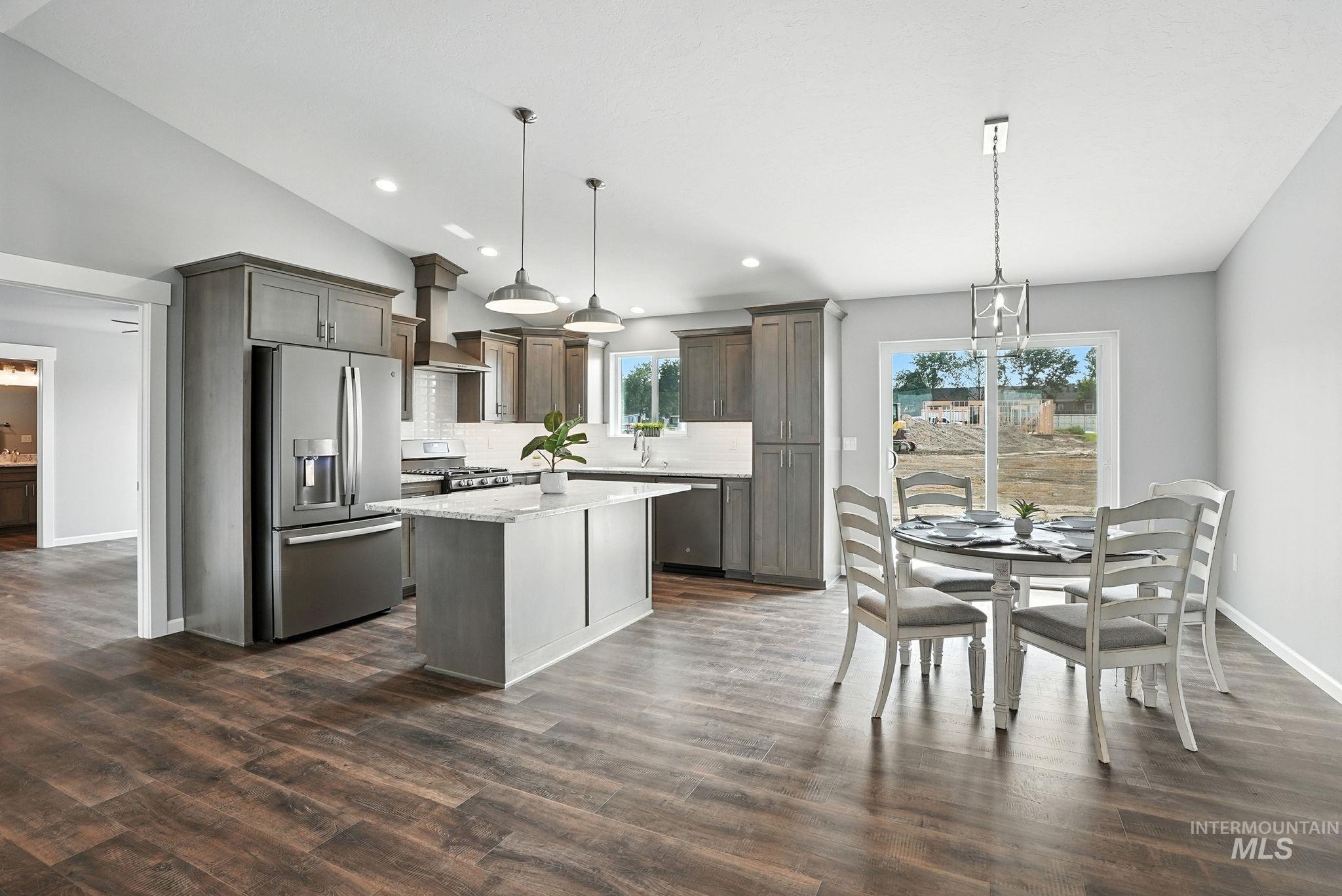 Kitchen with a chandelier, stainless steel appliances, a kitchen island, hanging light fixtures, and recessed lighting